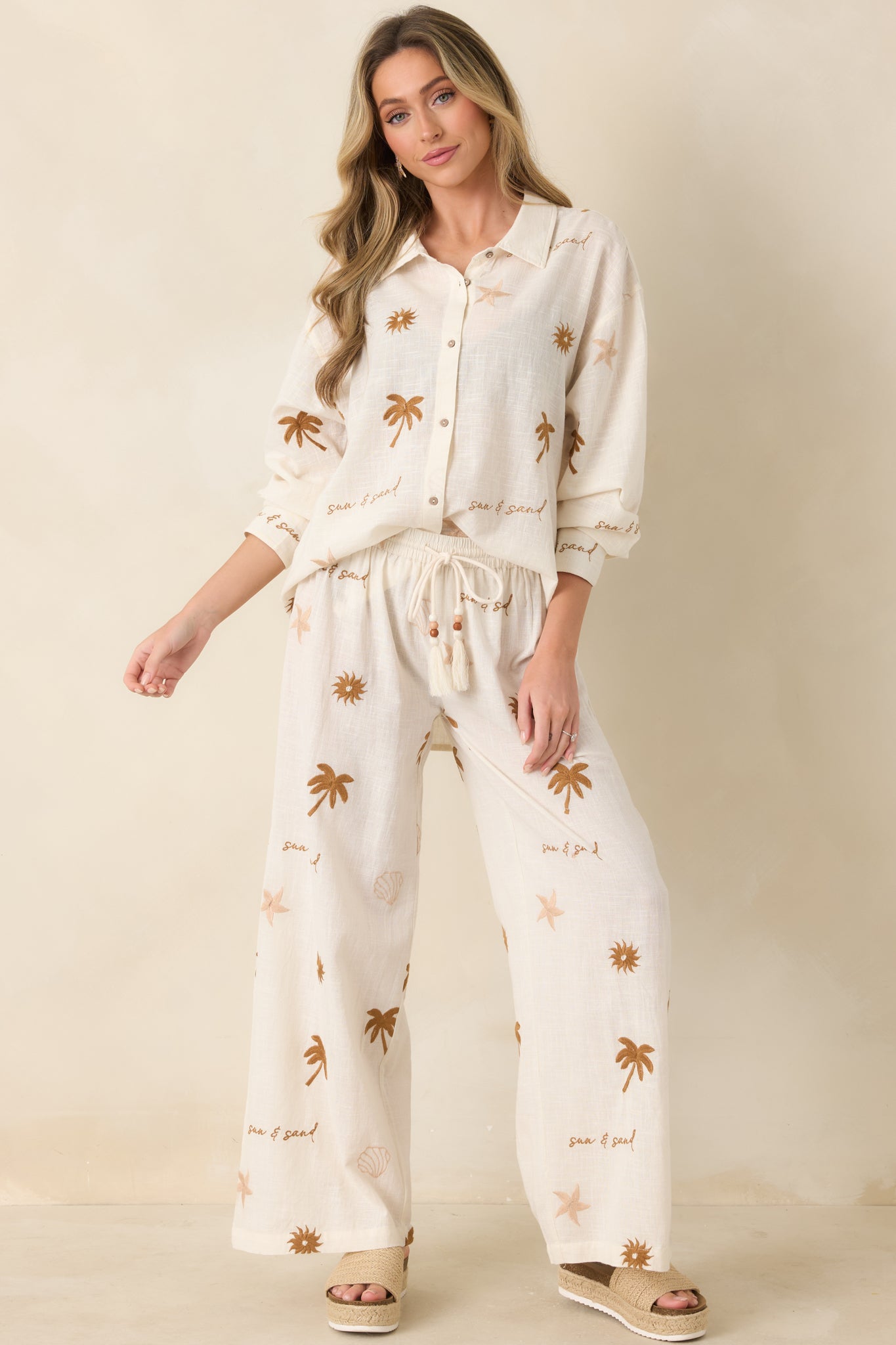 Light beige cotton pants with elastic waistband, drawstring tie, and wide leg silhouette.