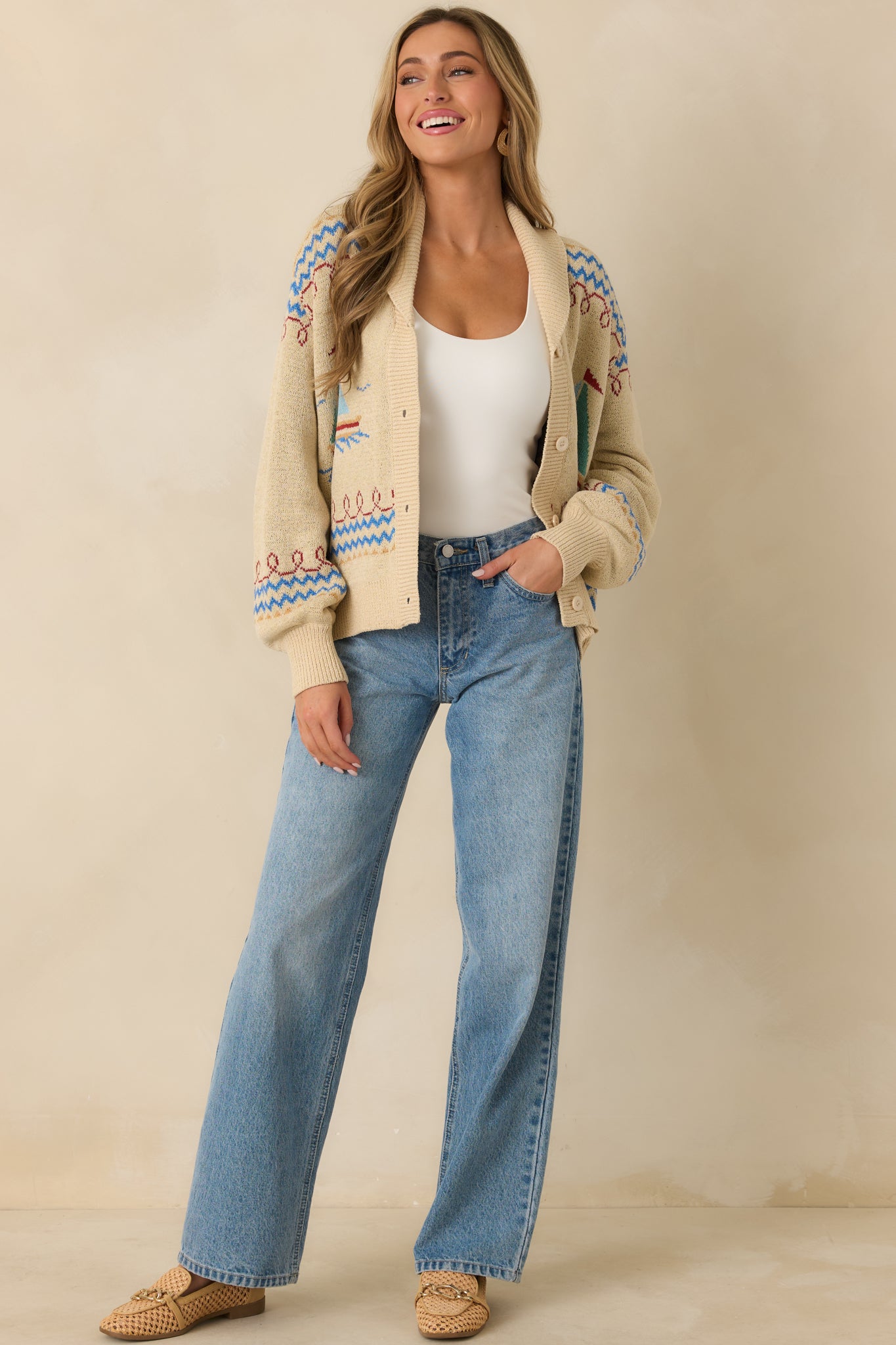 Front view of a light beige knit cardigan with a nautical-inspired pattern, button-up front, and long sleeves.