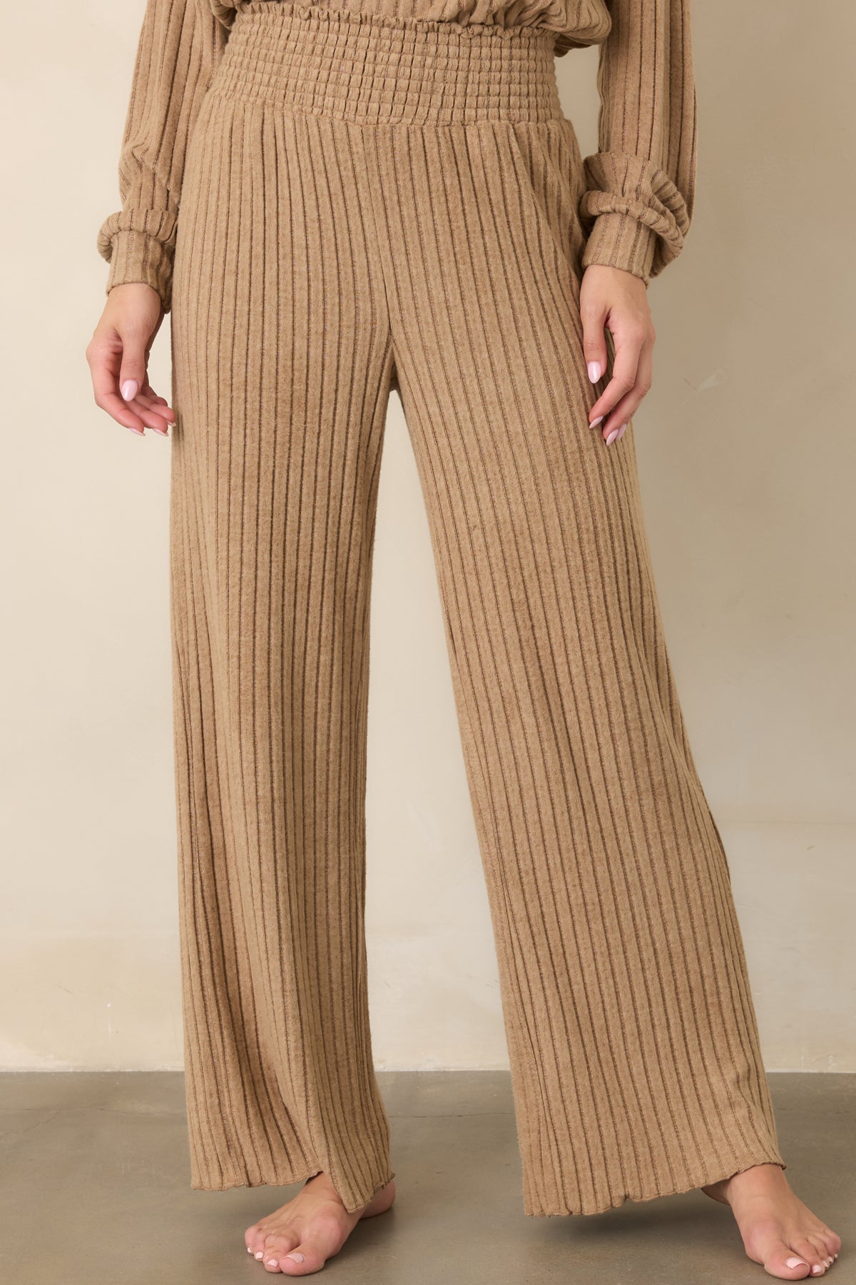 Light beige silky rib pants with a high-rise smocked waistband and relaxed wide-leg shape.