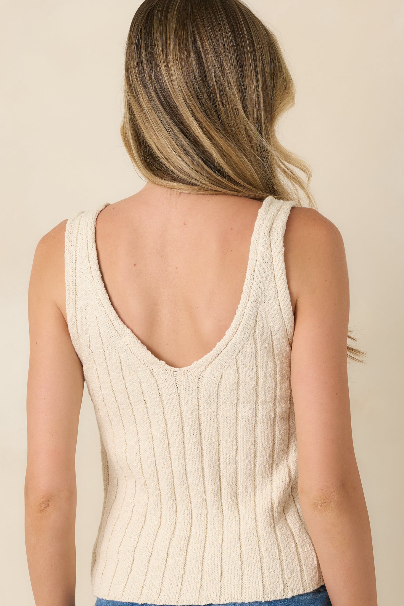 Back view of light beige sweater top featuring fine ribbed detailing.
