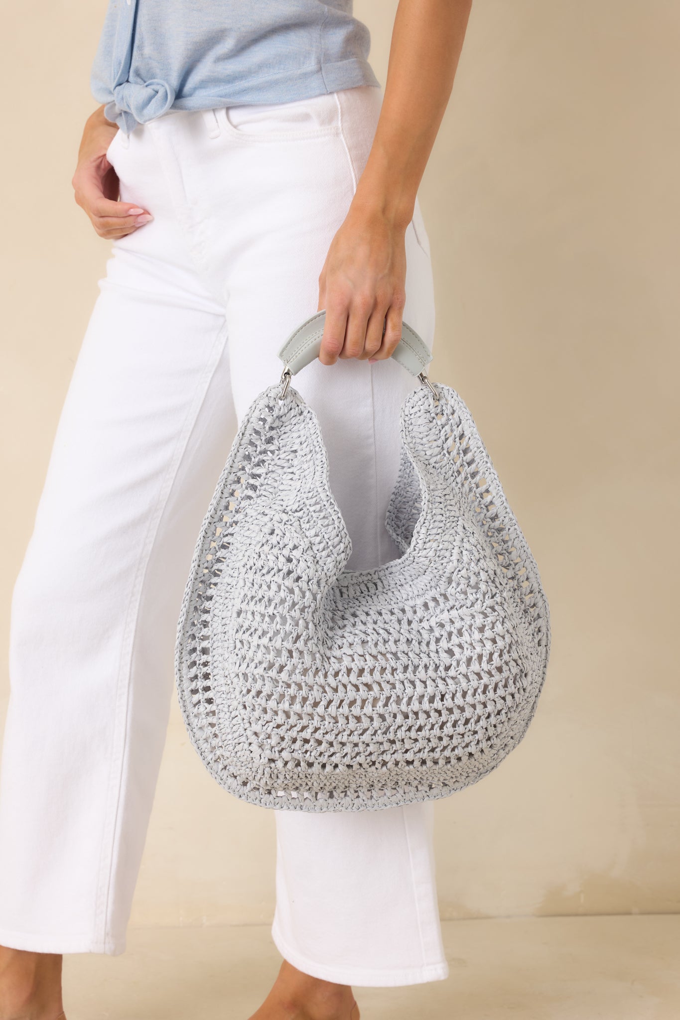Light blue woven handbag highlighting the open-knit pattern, curved silhouette, and sturdy top handle.