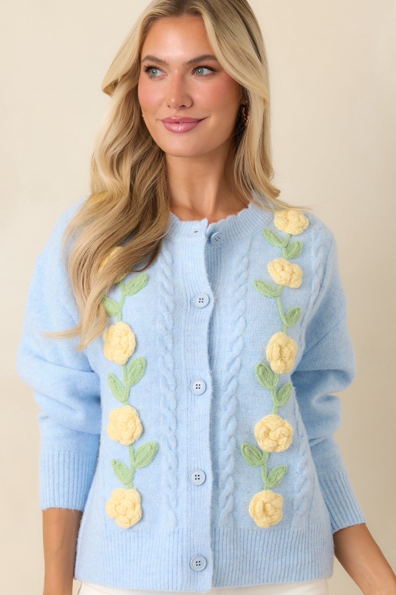  Light blue cardigan featuring delicate floral appliqué designs and ribbed trim along the edges.