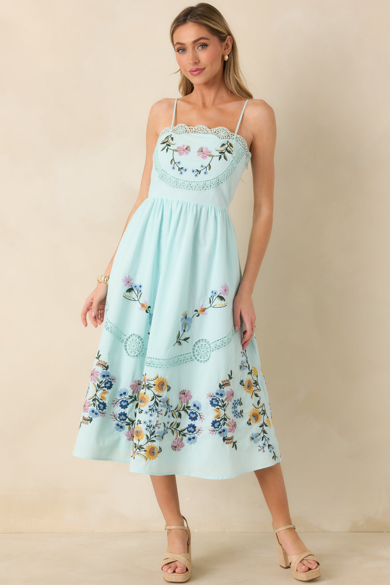 Light blue dress with multicolor floral embroidery, open-ladder lace panels, adjustable straps, and side pockets.