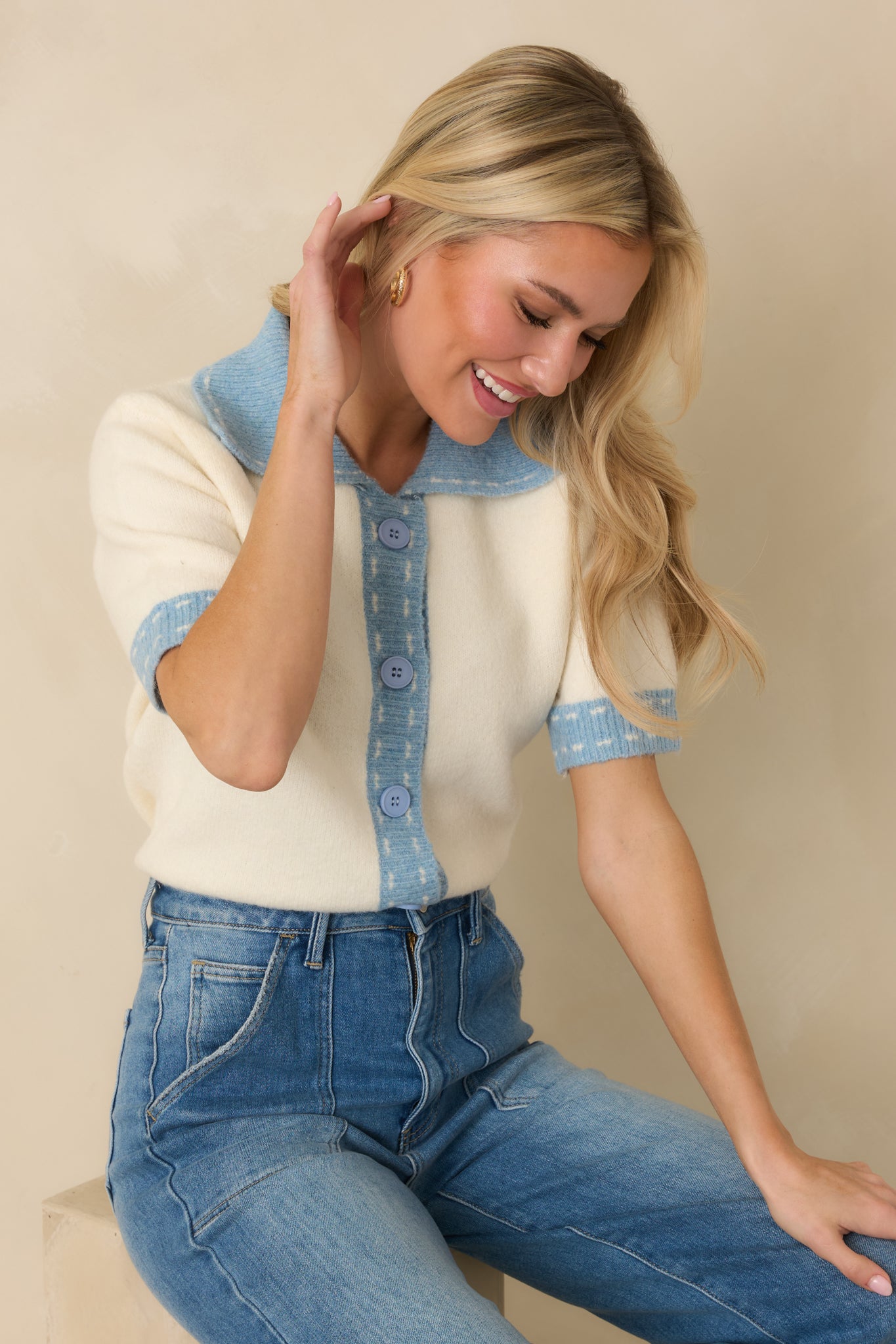 Light blue edging accenting the sleeve cuffs and hem against the smooth ivory stretch-knit fabric.