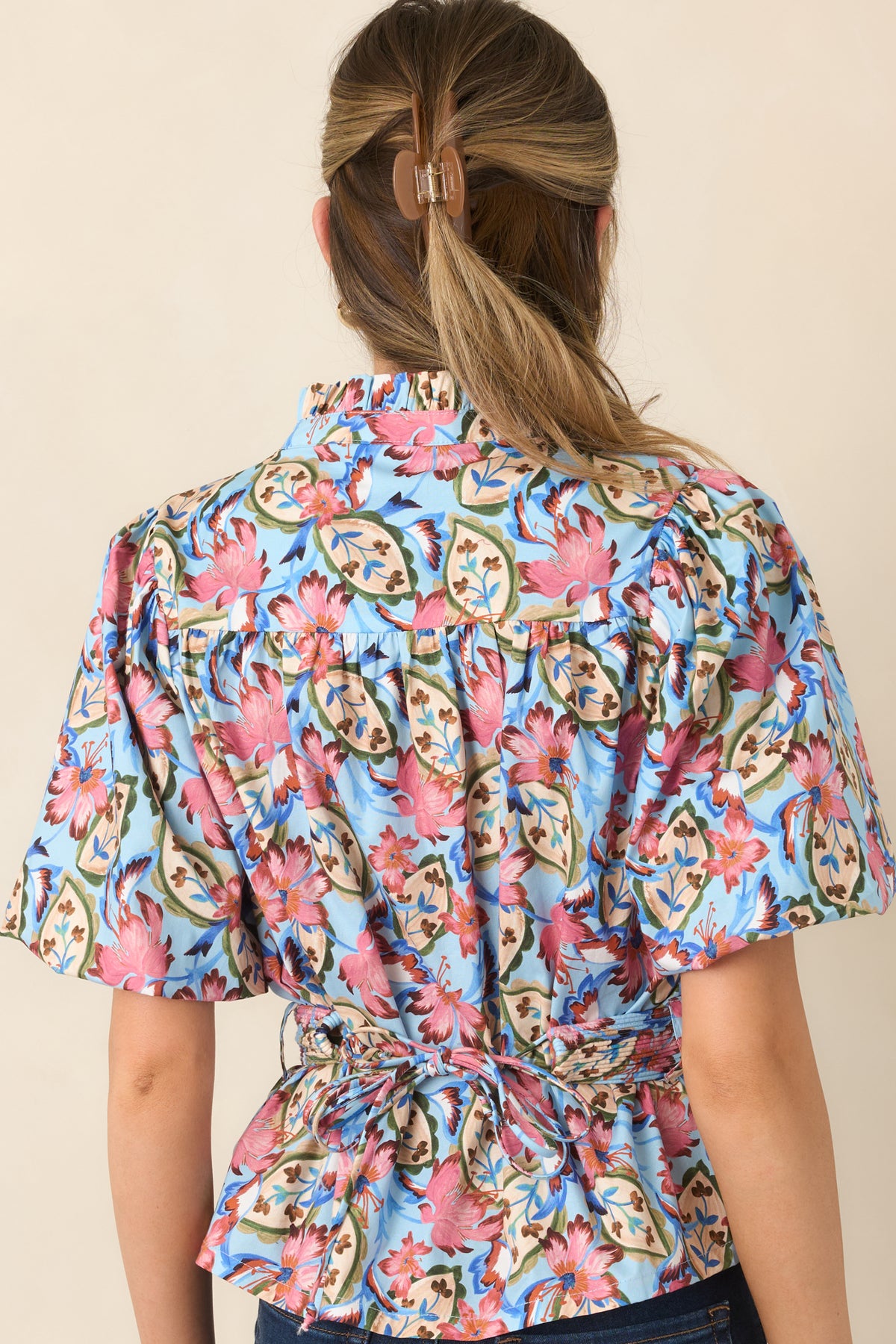 Rear of the light blue floral blouse featuring gathered back yoke detailing and short sleeves.