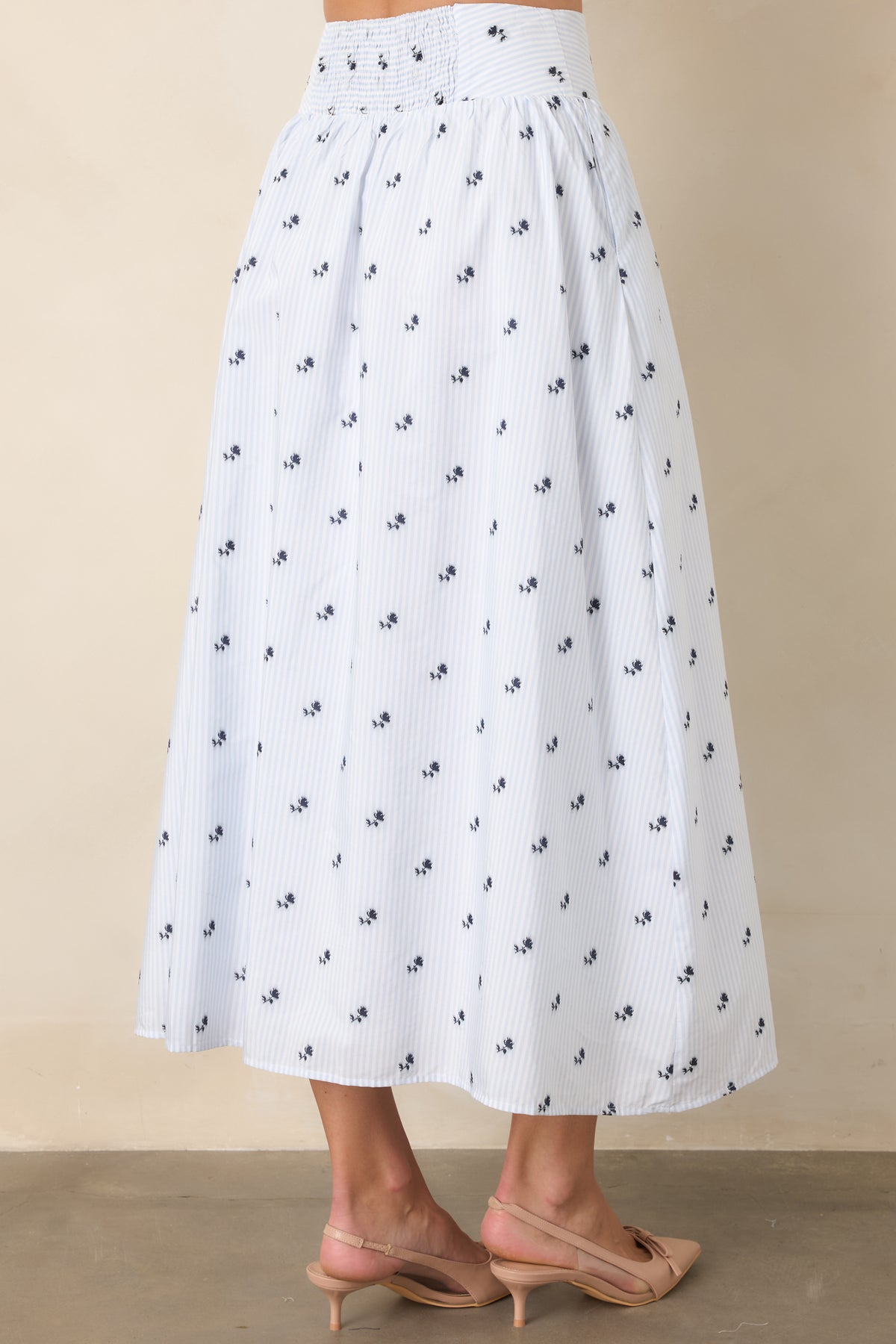Rear view of the light blue floral skirt showing the smocked waistband, fine stripes, and softly gathered shape.