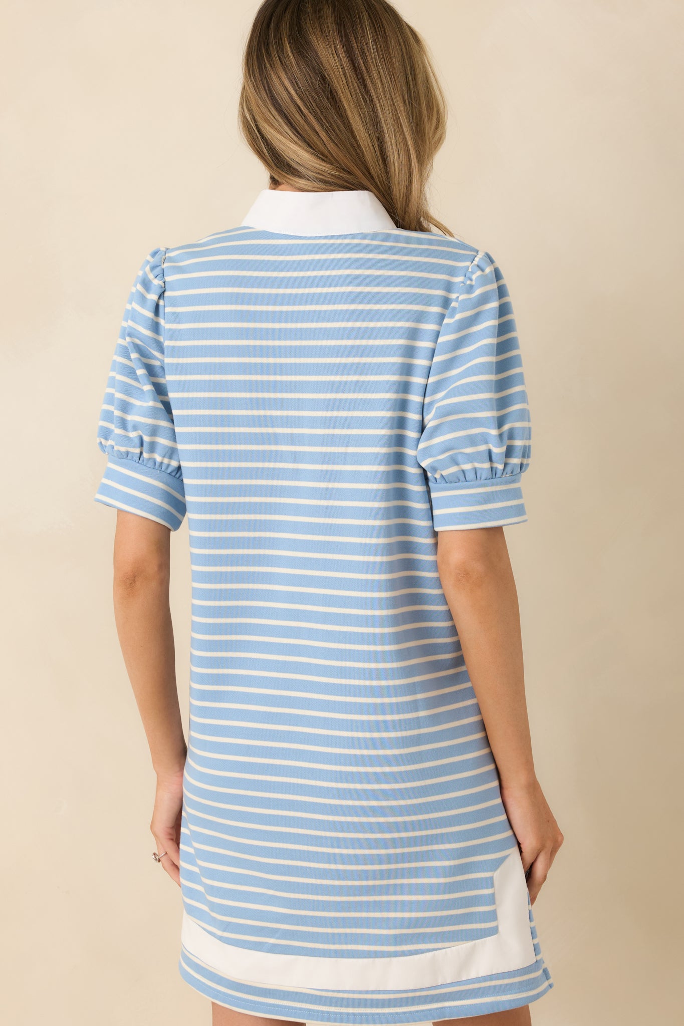 Light blue knit mini dress with contrast neckline trim and side pockets continuing across the rear.