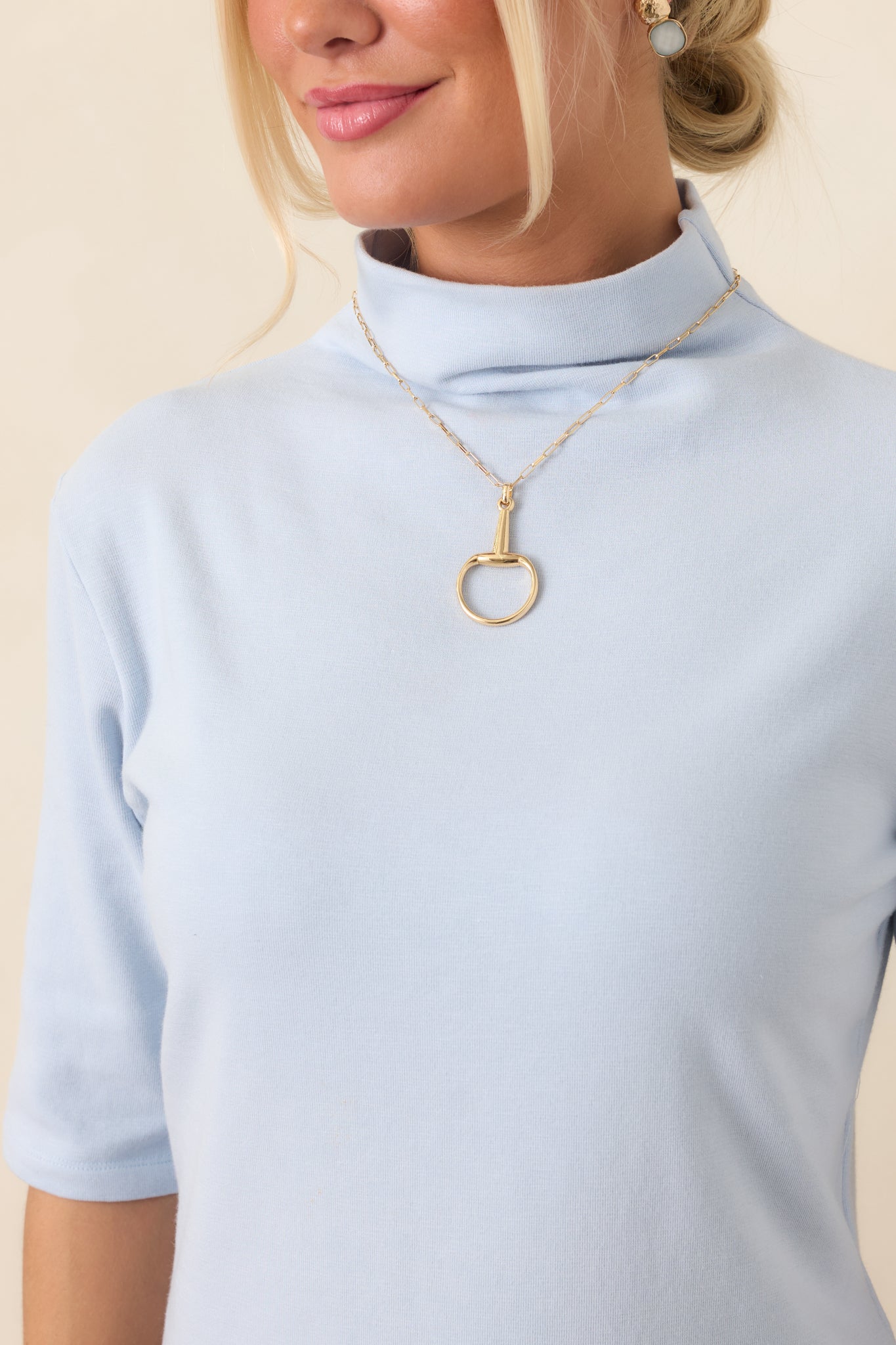 Close-up of the light blue knit top revealing its smooth construction, softly refined texture, and structured mock neckline.