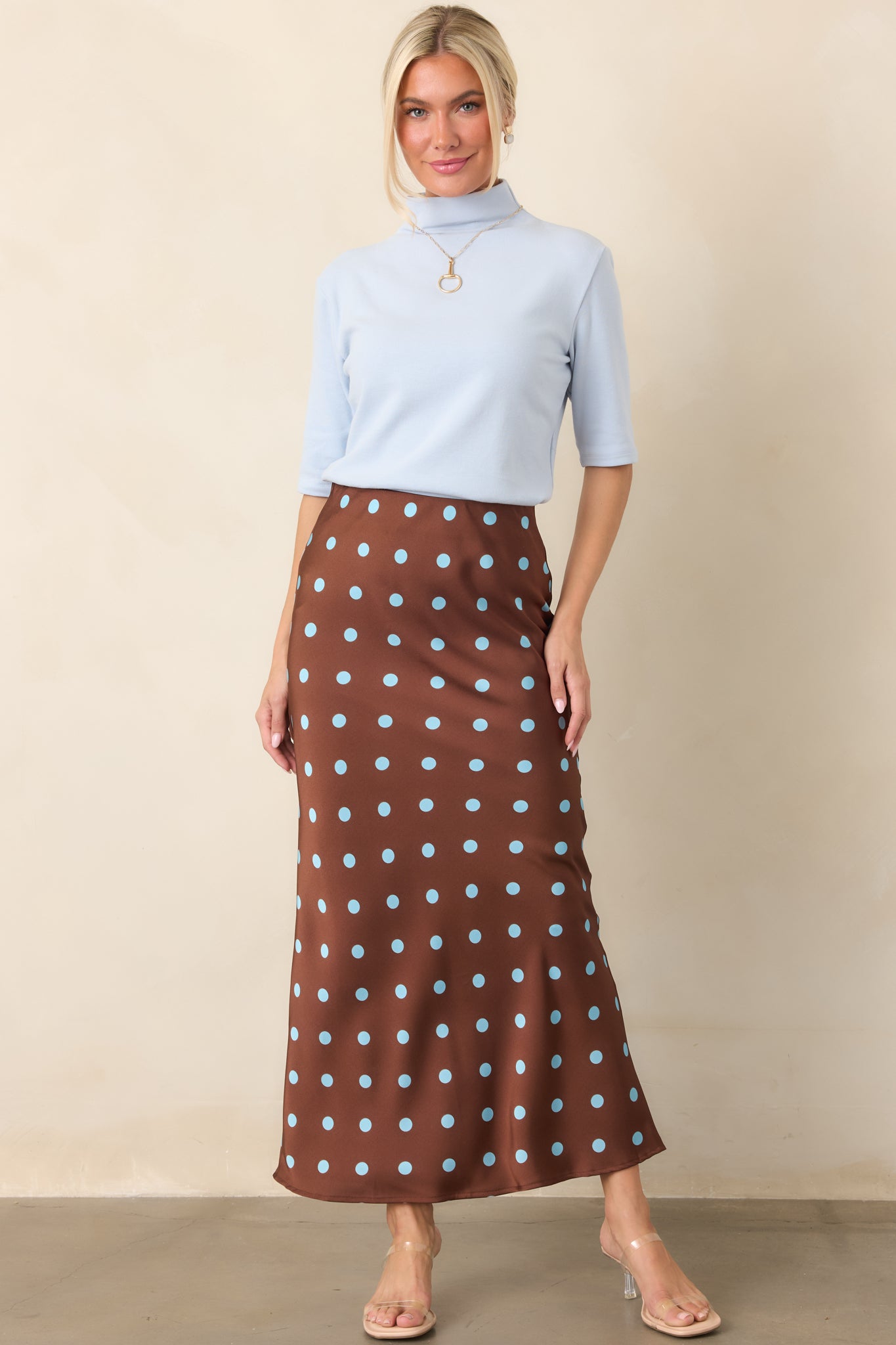 Light blue knit top featuring a refined mock neckline, elbow-length sleeves, and a gently fitted silhouette.