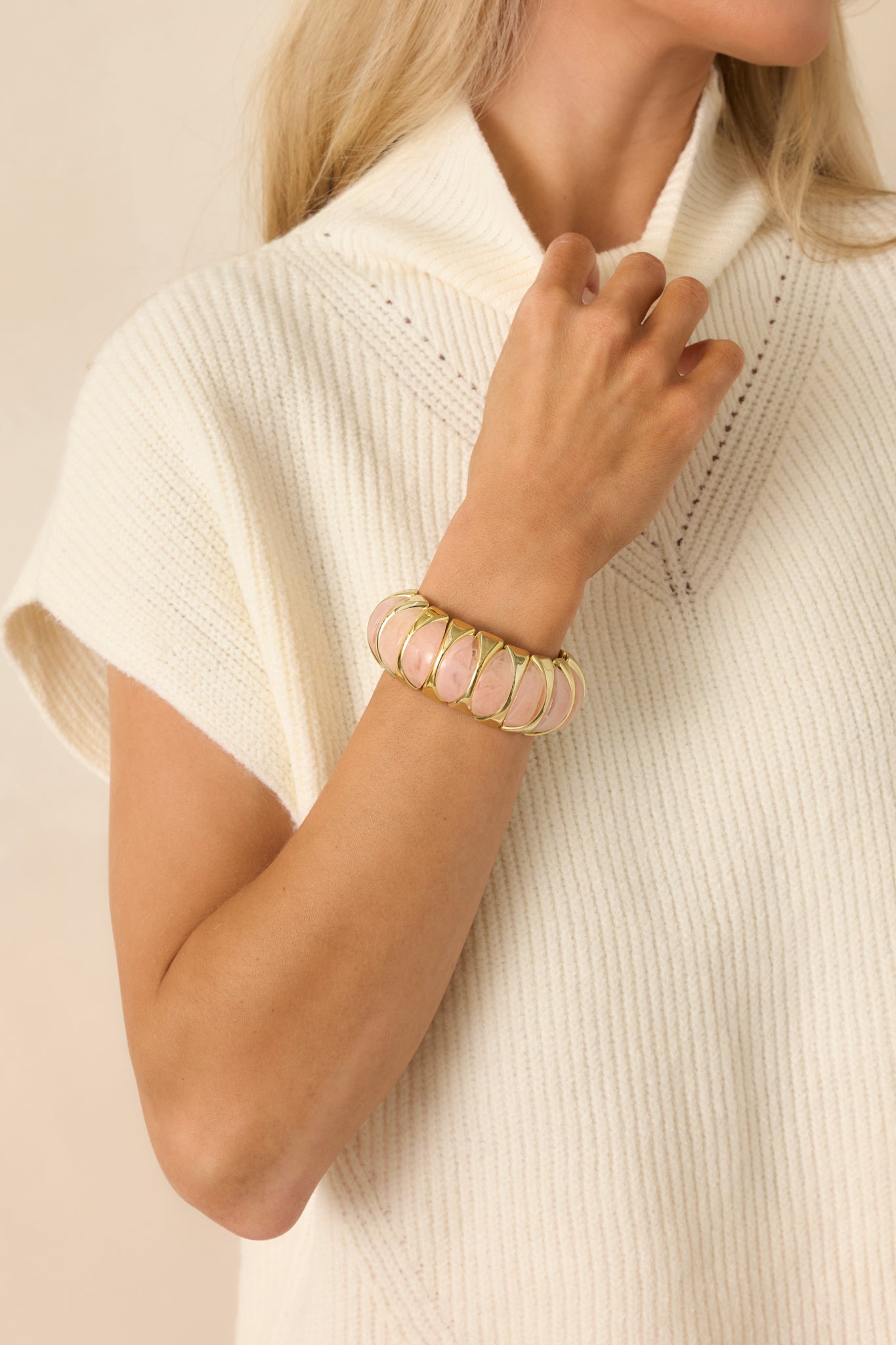 Cropped view of the light pink and gold stretch bracelet featuring sculptural pink beads held in polished gold-tone links.