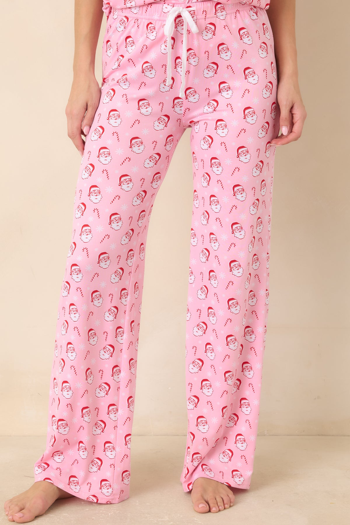 Light pink pajama pants showcase the festive Santa motifs repeated across the fabric and relaxed leg shape.