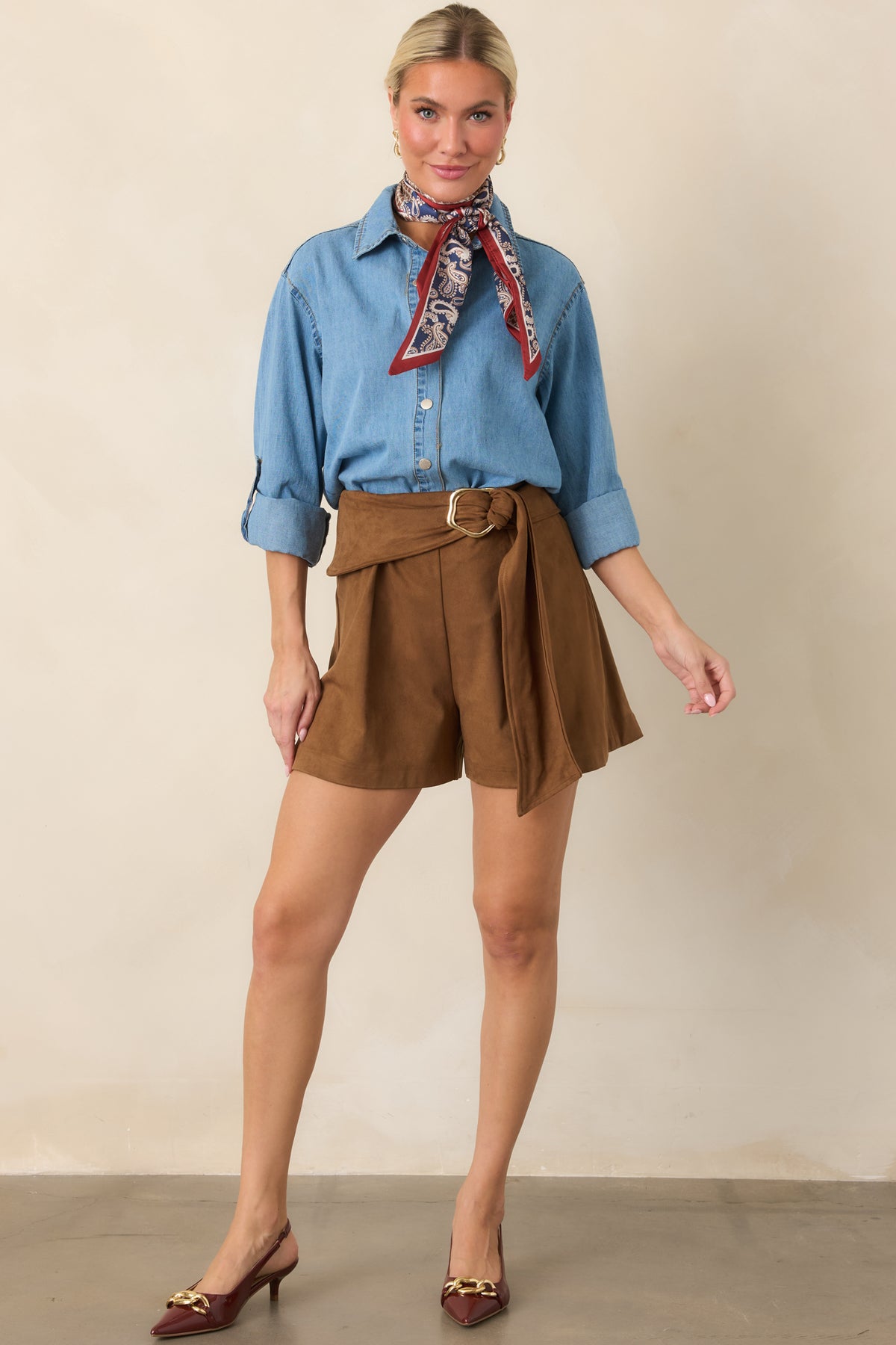 Light-wash cotton top featuring a collared neckline, button-front closure, roll-tab sleeves, and curved high-low hem.