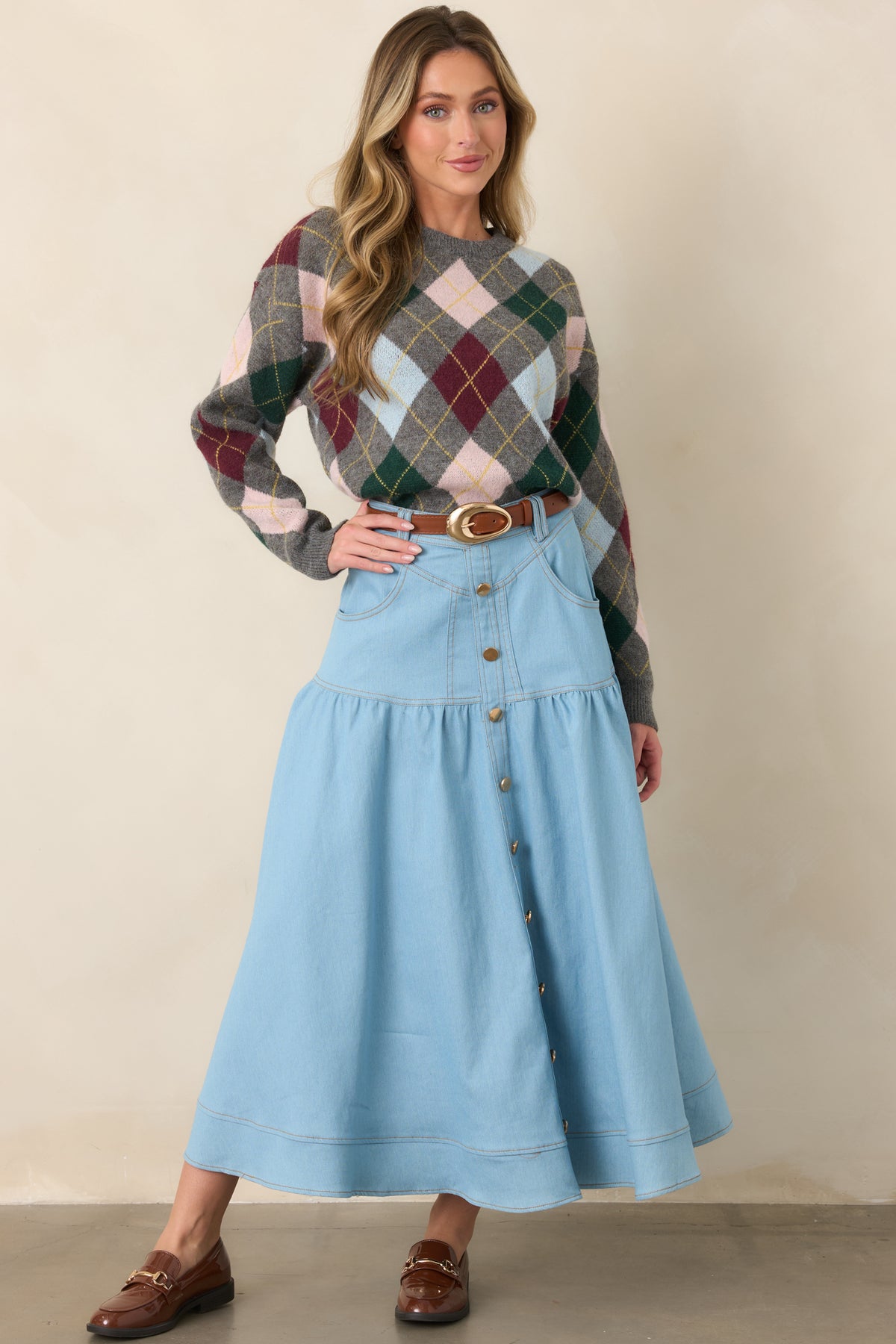 Light wash denim maxi skirt with a structured high-rise waist, gold-tone button front, softly flared tiers, and a wide hem for graceful movement.
