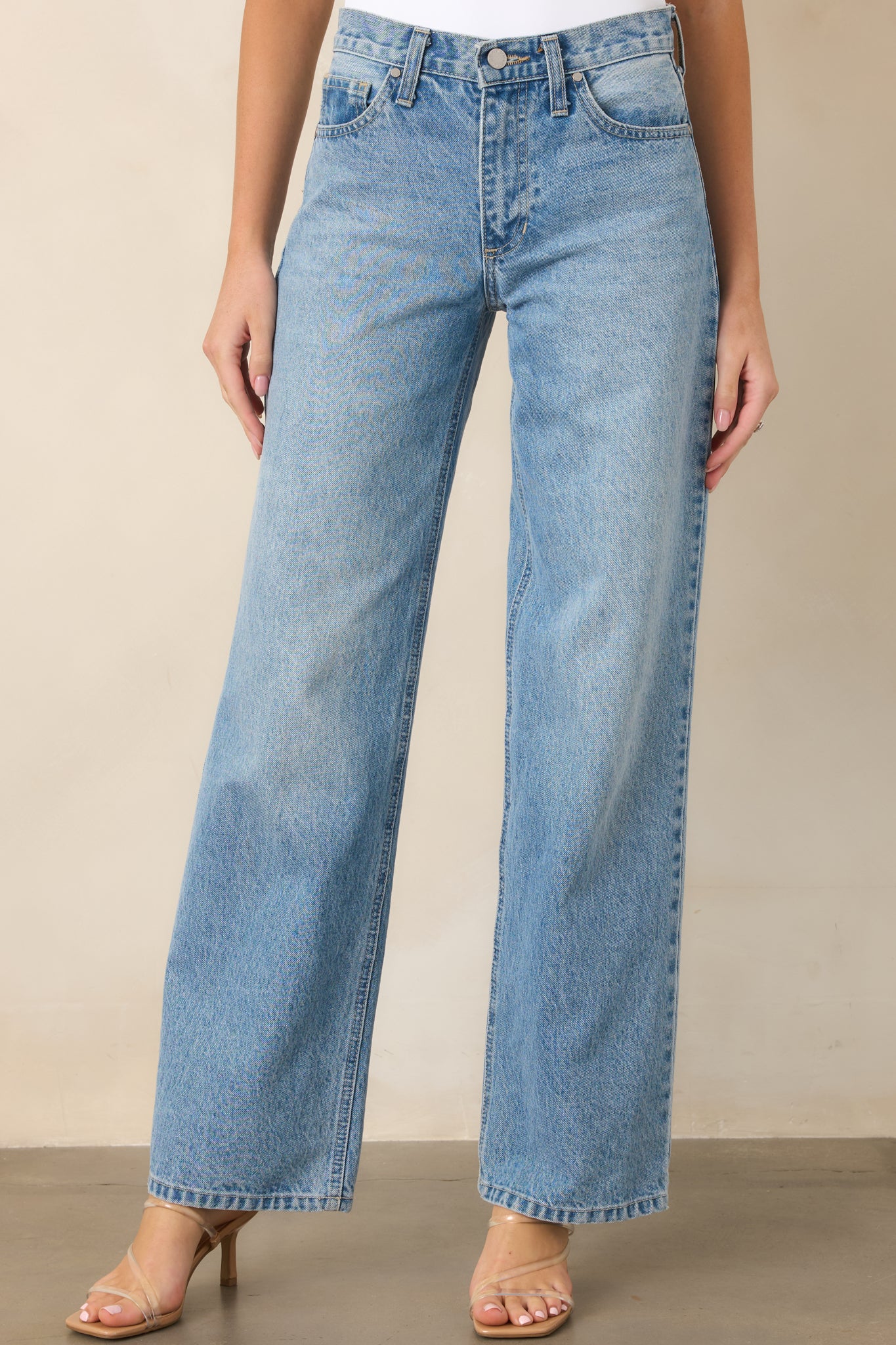 Close view of the light wash denim highlighting the high waist and classic button and zip closure.