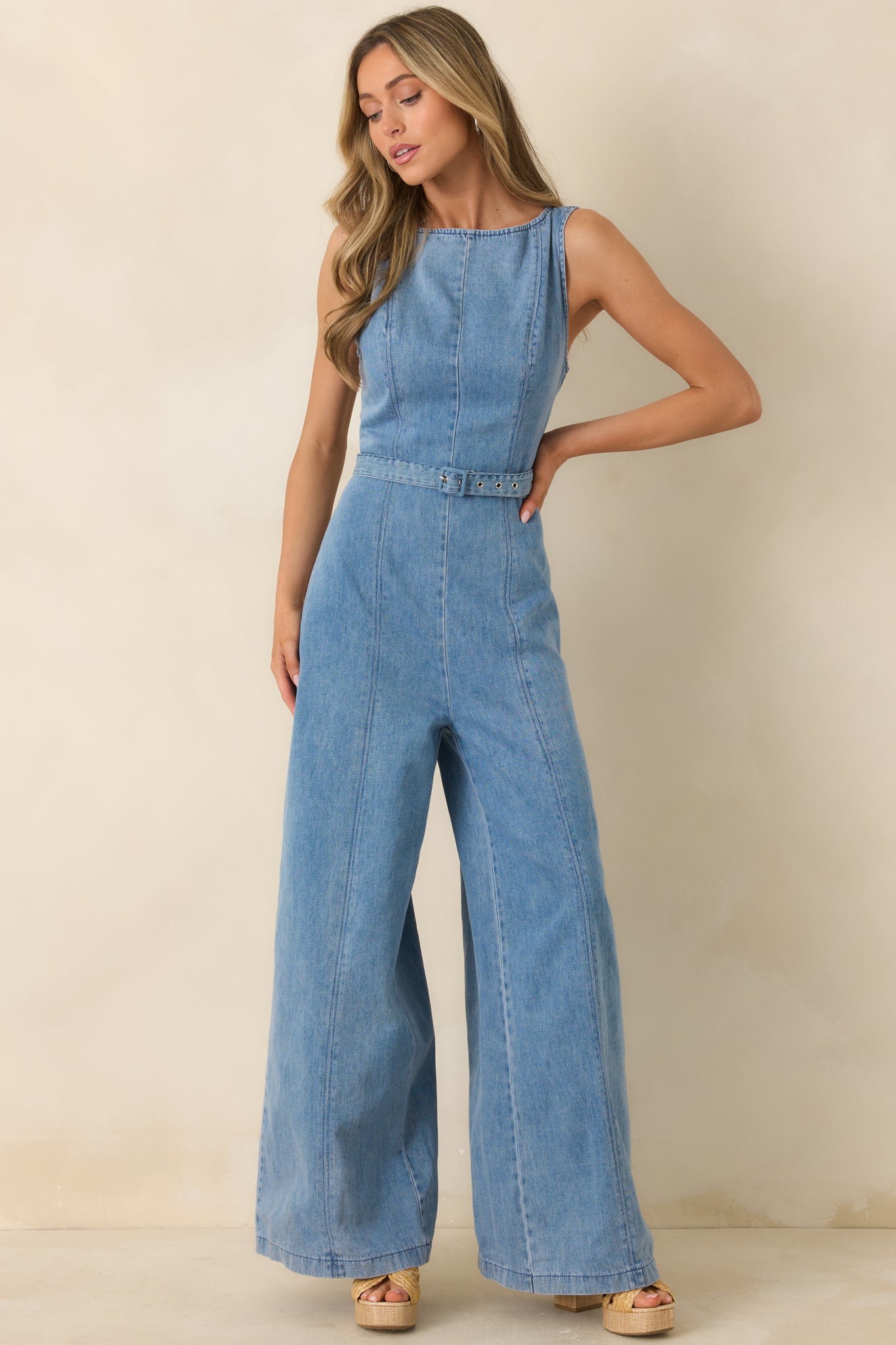 Light wash jumpsuit with clean high neckline, defined waist, and structured seam accents throughout