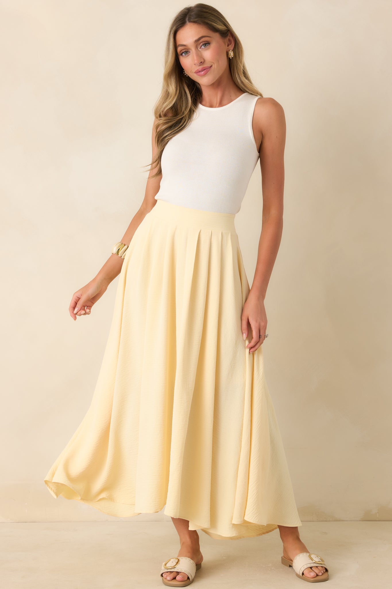 Light yellow skirt with a sweeping maxi length, fluid shape, and curved hem detail for added movement.