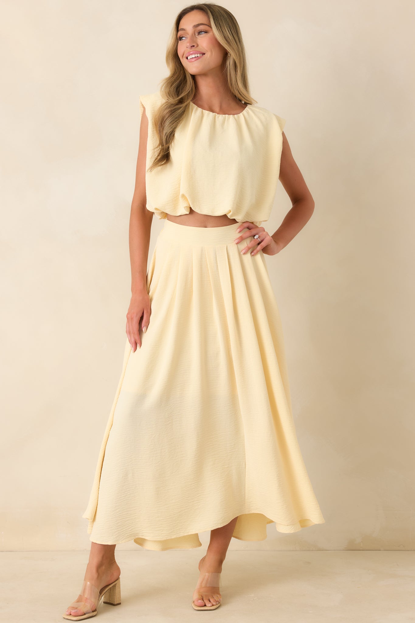 Light yellow sleeveless crop top with a billowy silhouette, softly ruched neckline, and fitted elastic hem.