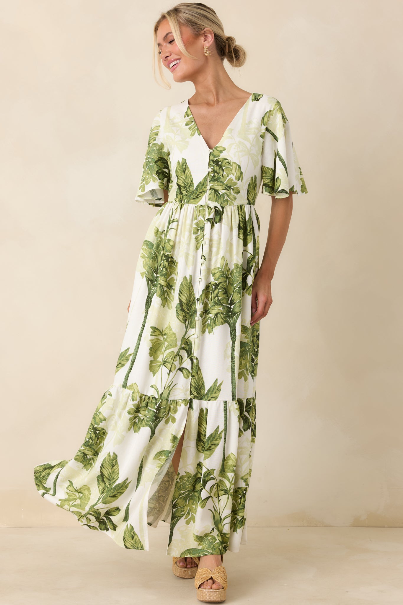 Lightweight ivory maxi dress with tropical print, fluttered sleeves, button-front accent, and full-length tiered skirt with fluid drape.