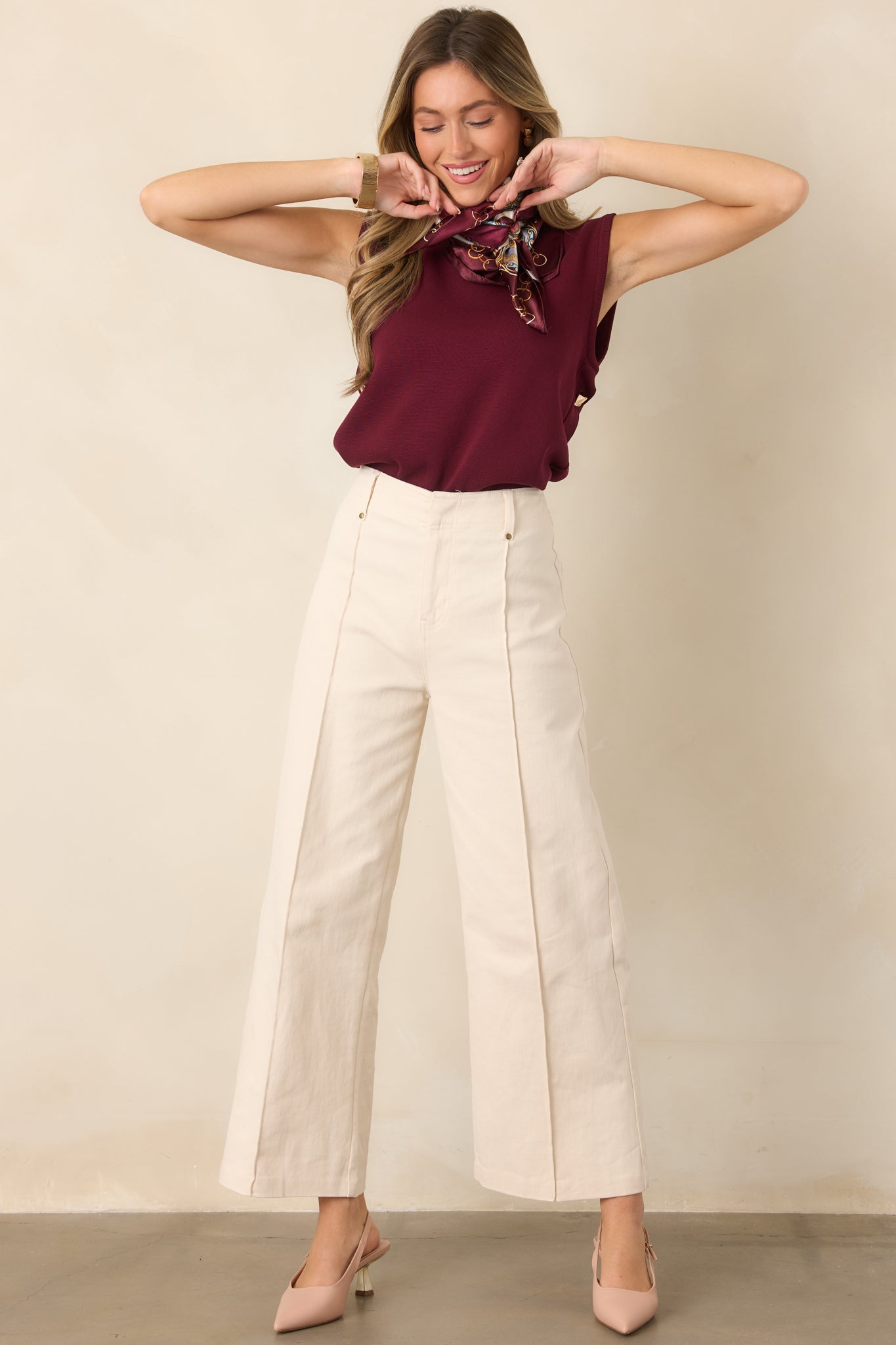 Elevated sleeveless knit top showcasing its breathable lightweight construction, flowing drape, classic crew neckline, and decorative side button detail.
