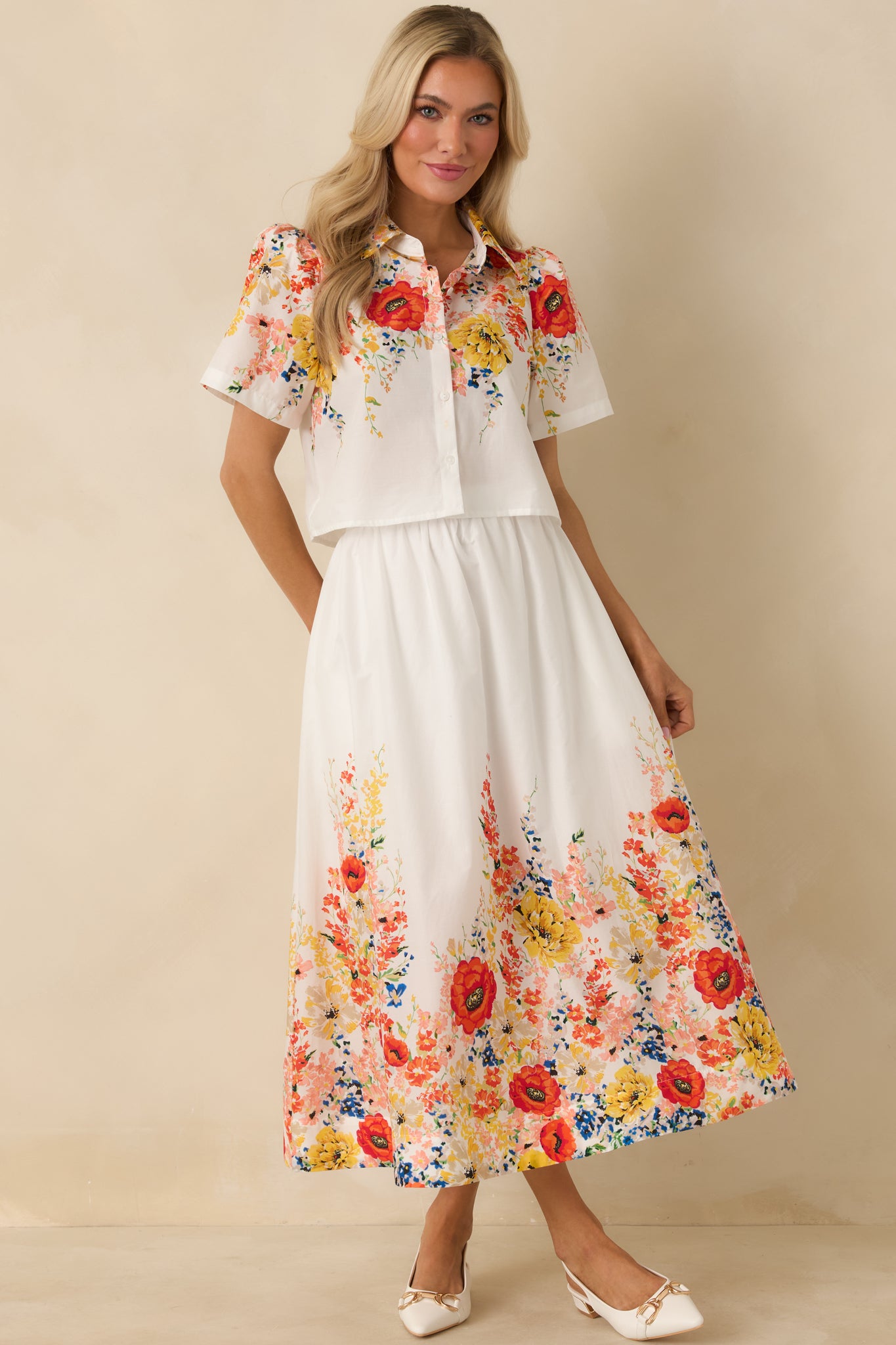 Lightweight white maxi skirt featuring a pull-on elastic waist, easy drape, and a colorful floral border at the hemline.