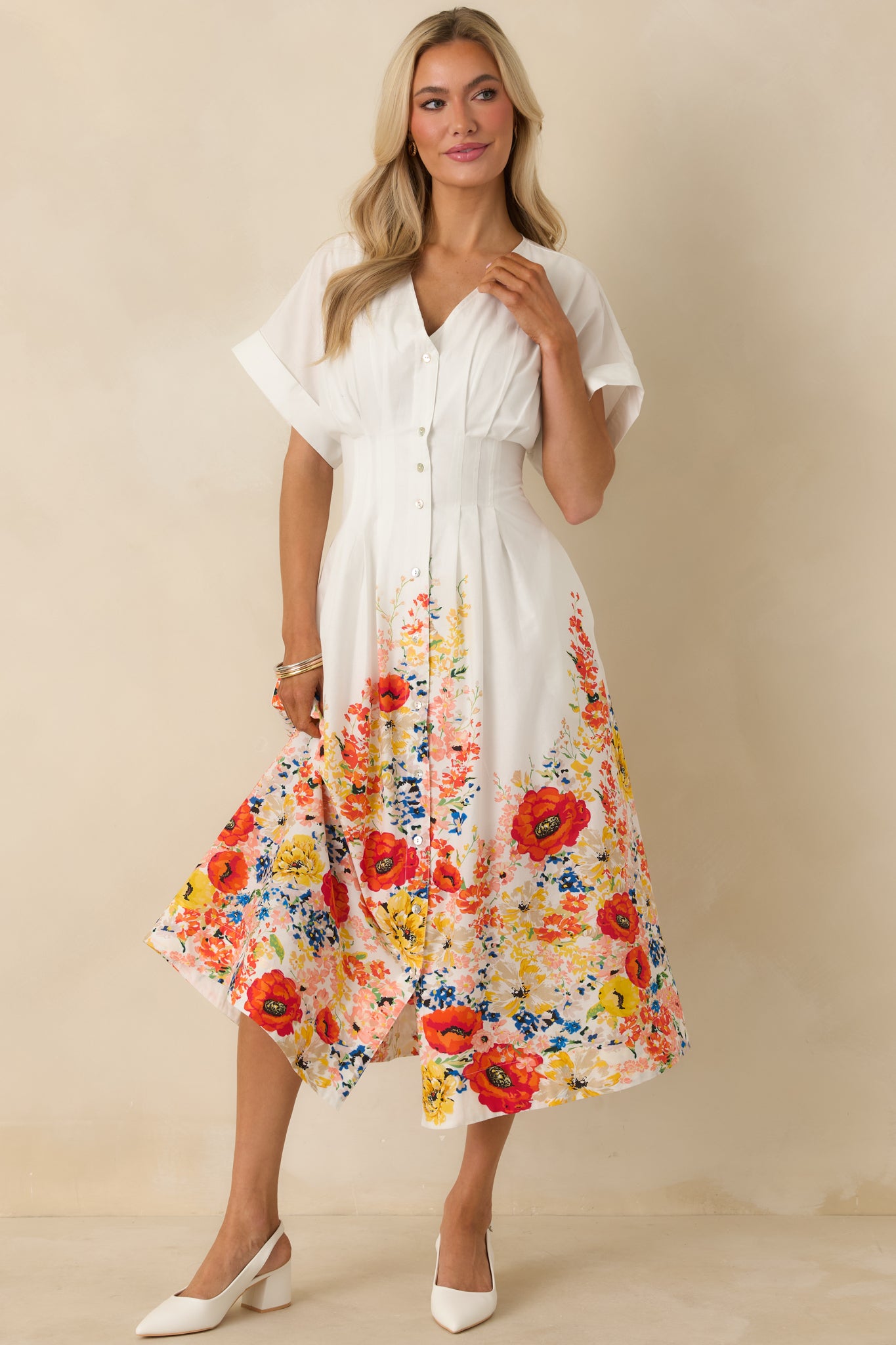 Lightweight white midi dress featuring a button-down front, defined waist seam, and colorful floral detailing at the hemline.