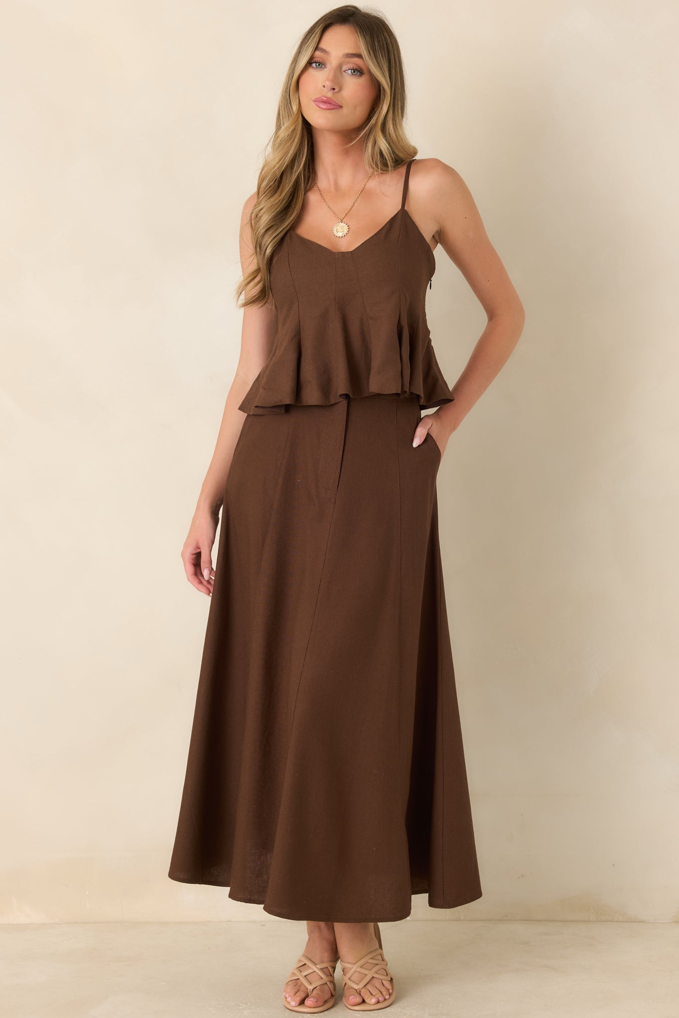 Linen and cotton blend peplum top featuring a fitted paneled bodice, adjustable spaghetti straps, a softly shaped neckline, and a flowing flared hem.