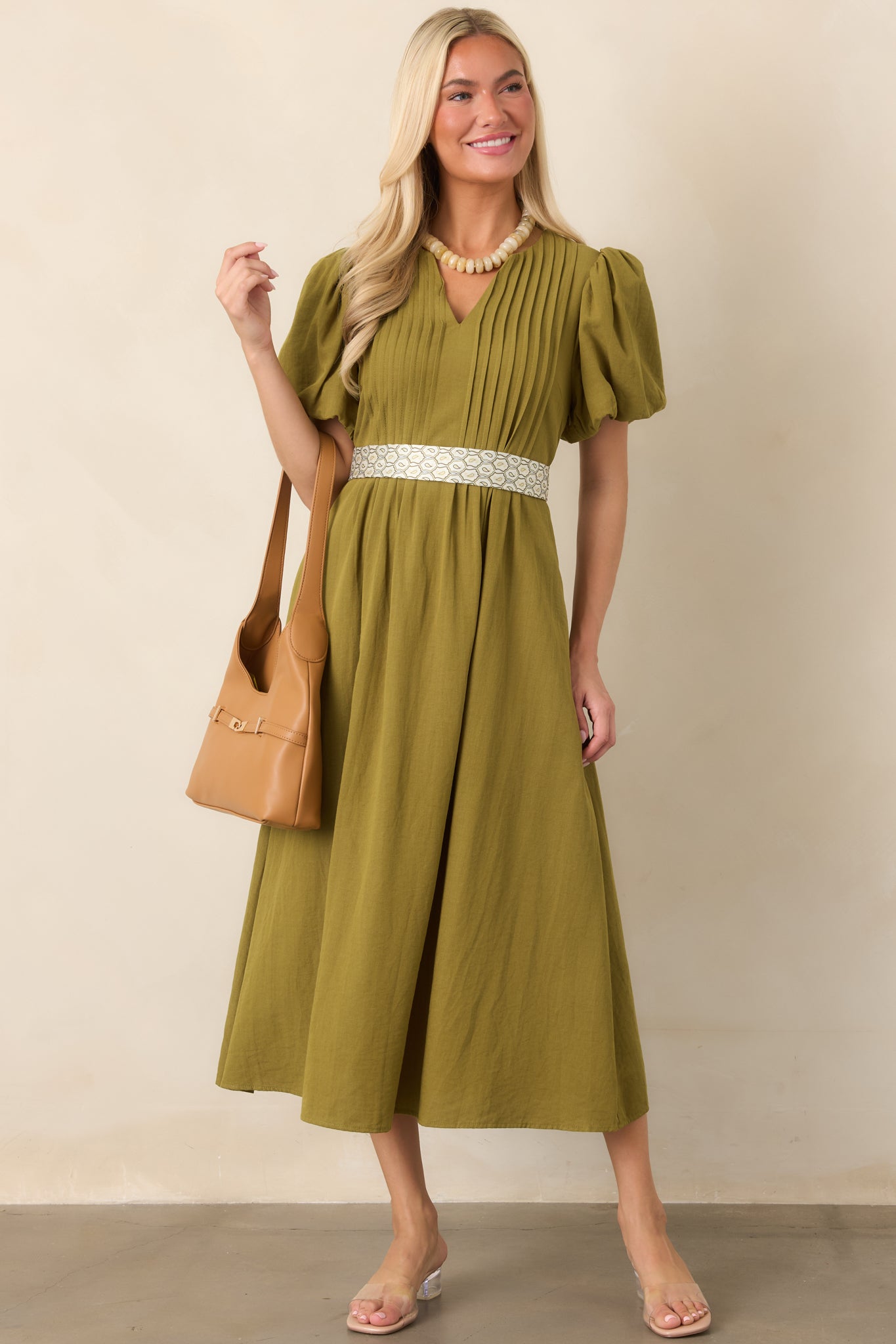 Linen-textured midi dress designed with a softly shaped V-neckline, gathered short puff sleeves, and a graceful skirt with practical side pockets.