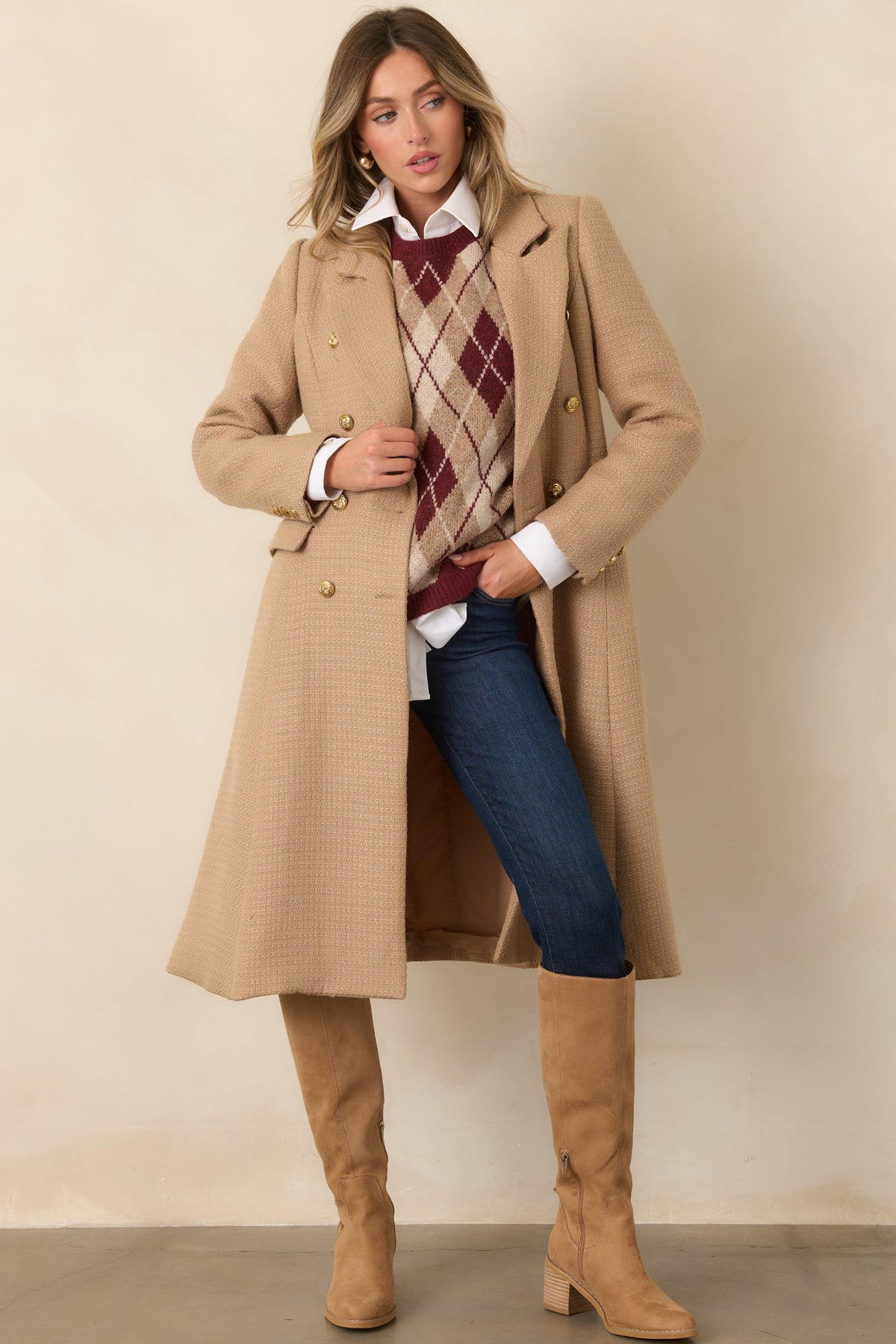 Long camel topcoat with a polished double-breasted front, structured shoulders, and button-accented cuffs.