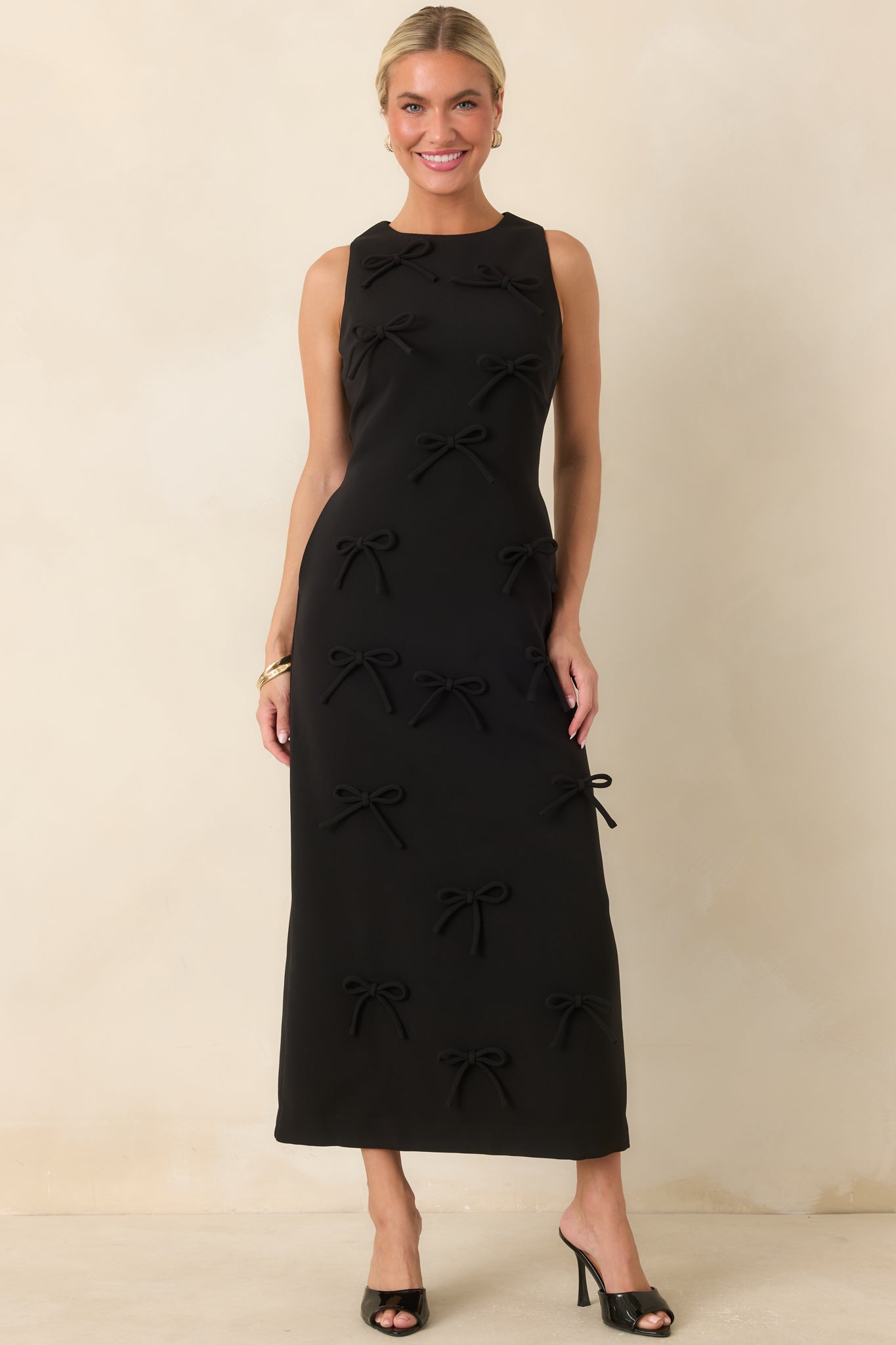 Long column dress showcasing a fitted bodice, sleek skirt, and textured tonal bow detailing throughout.