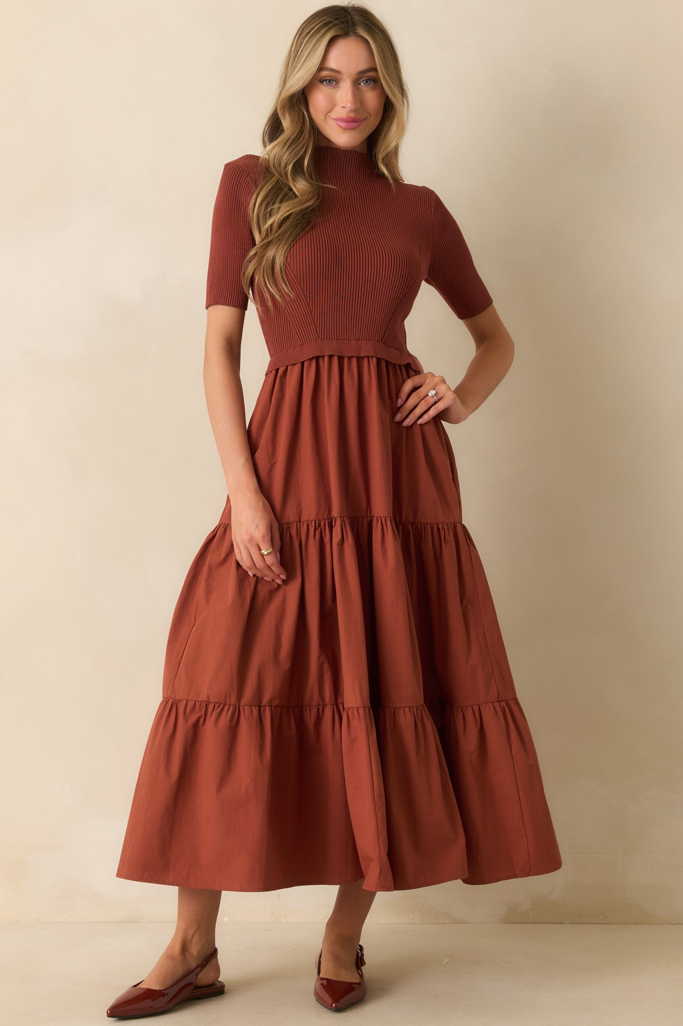 Long rust red dress with short sleeves and ruffle detail at the waist, pockets slightly visible.