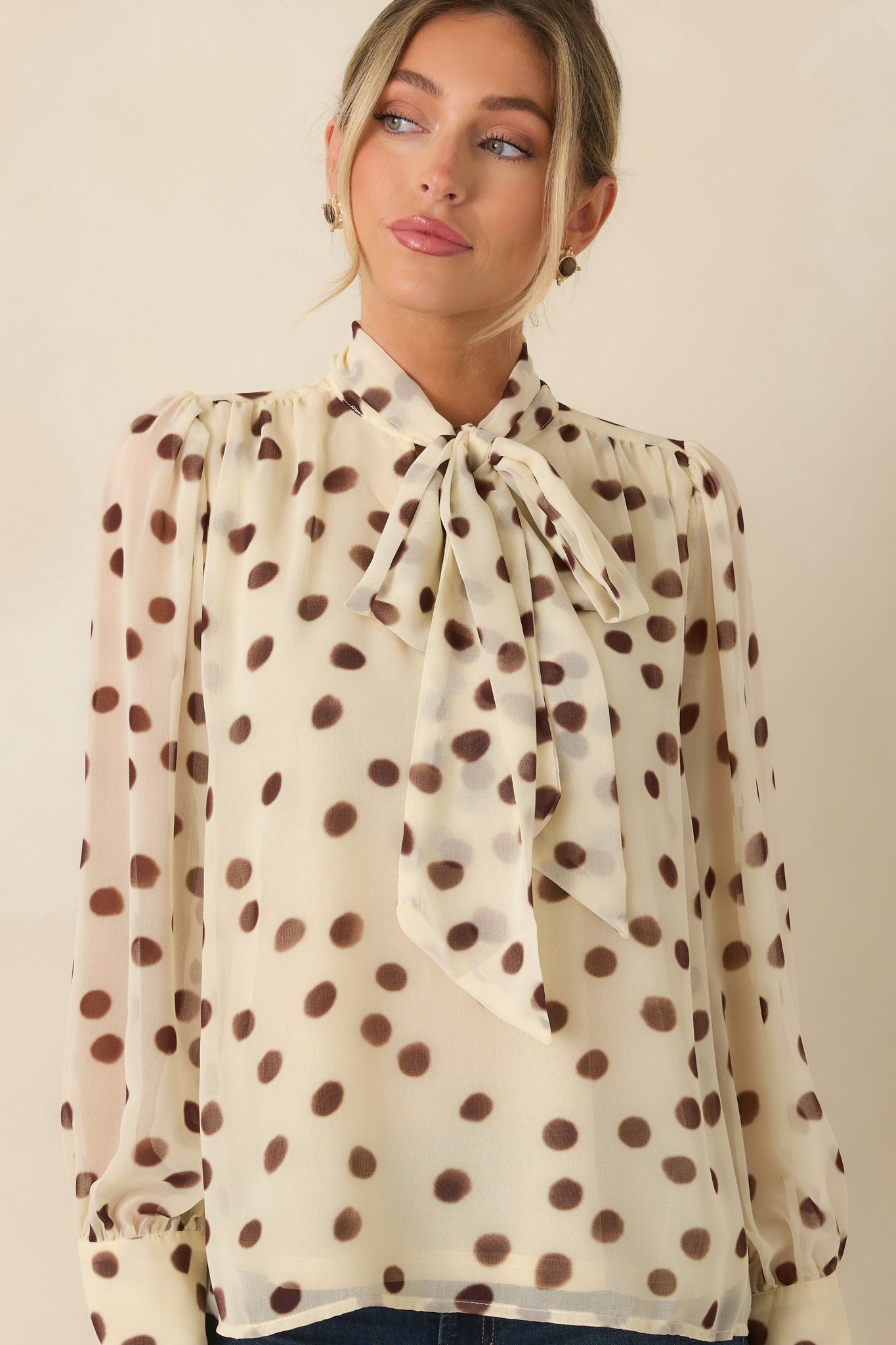 Close view of the long sleeve button cuffs and delicate chiffon construction of the polka dot blouse.