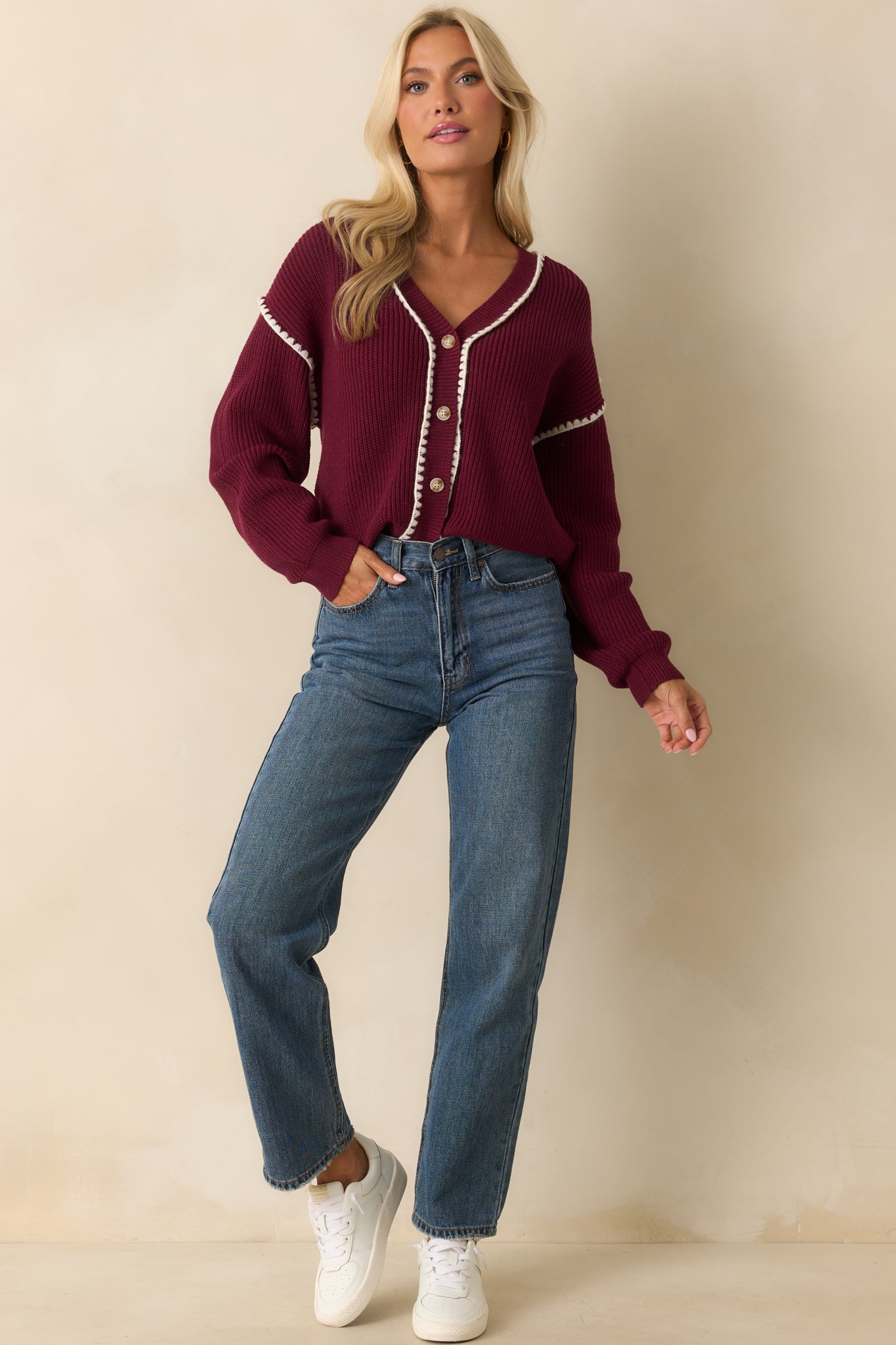 Long-sleeve maroon cardigan featuring contrasting white whipstitch trim along edges and sleeves.