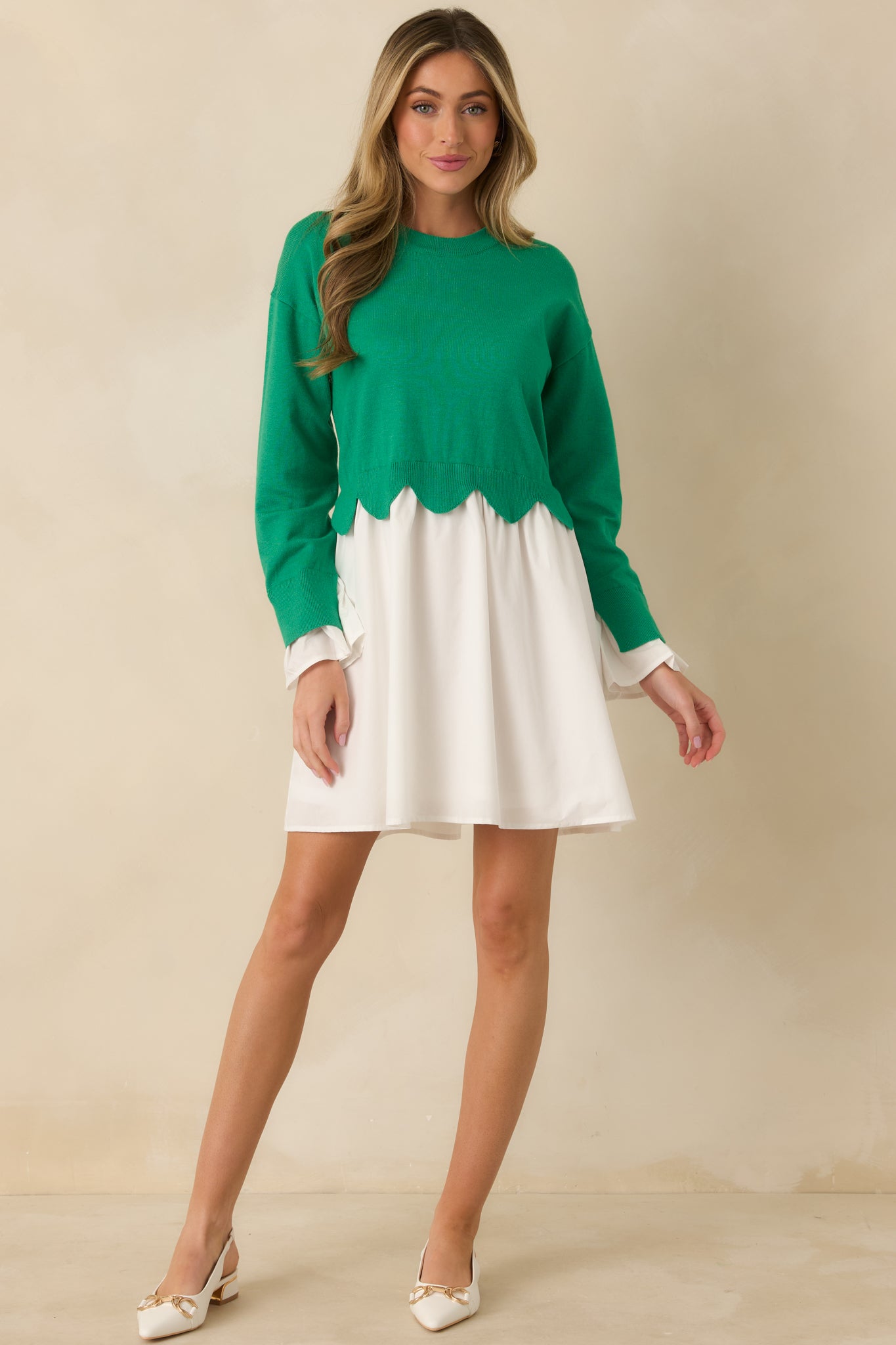 Green and white long sleeve mini dress shown from the front, showcasing the scalloped hem detailing at the waist.