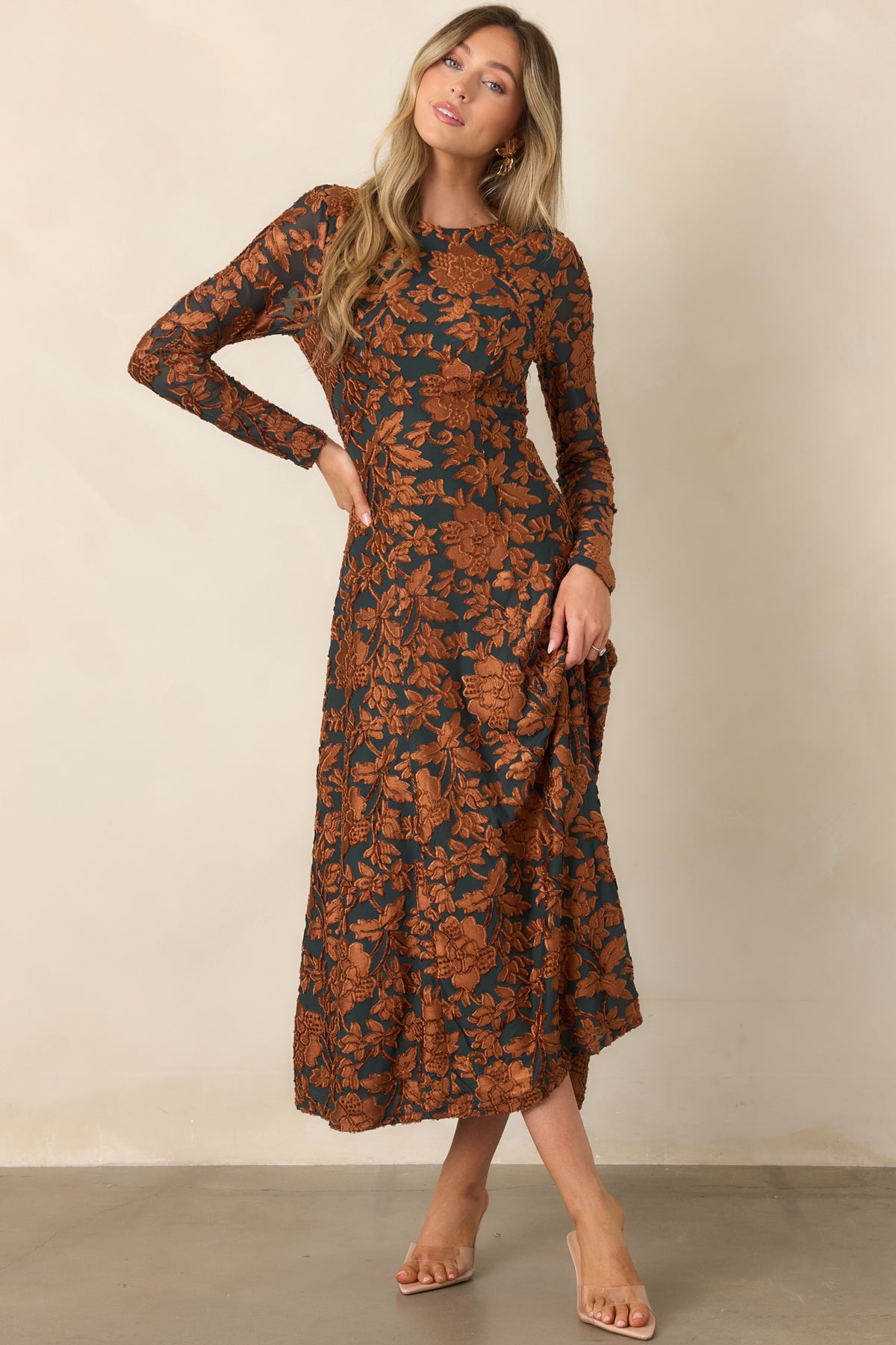 Long-sleeved deep green dress with dimensional copper floral motifs, a round neckline, and a flowing midi skirt.