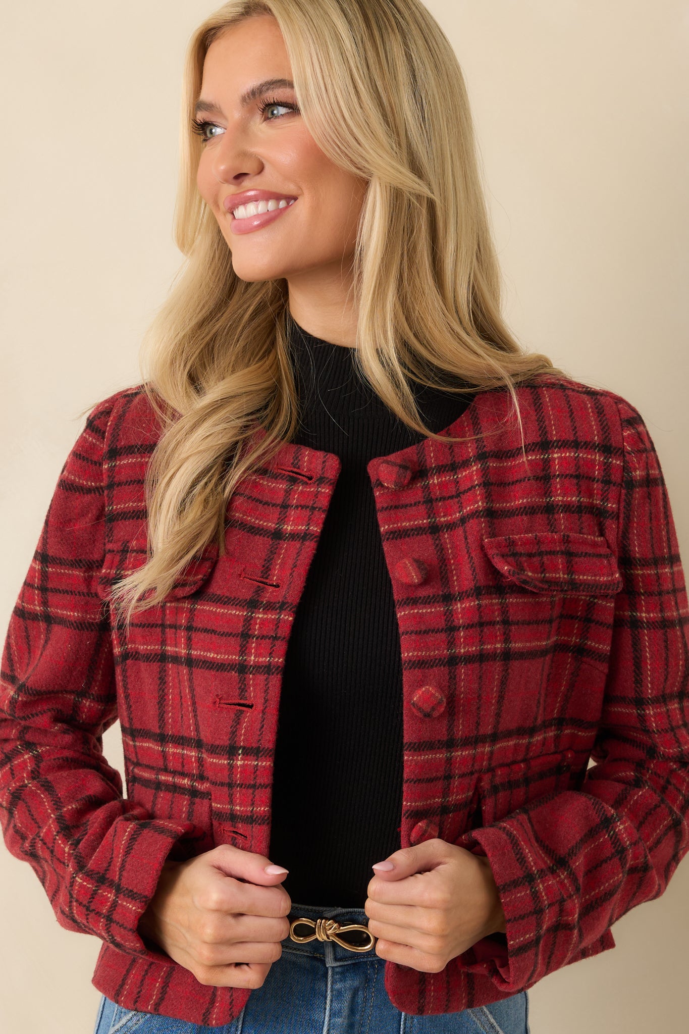 Focused look at long sleeves and woven plaid pattern on red jacket.