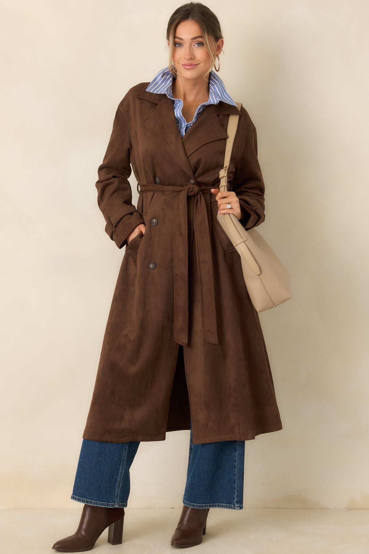 Longline coat features a notched collar, double-breasted button front, matching tie belt, and functional side pockets.