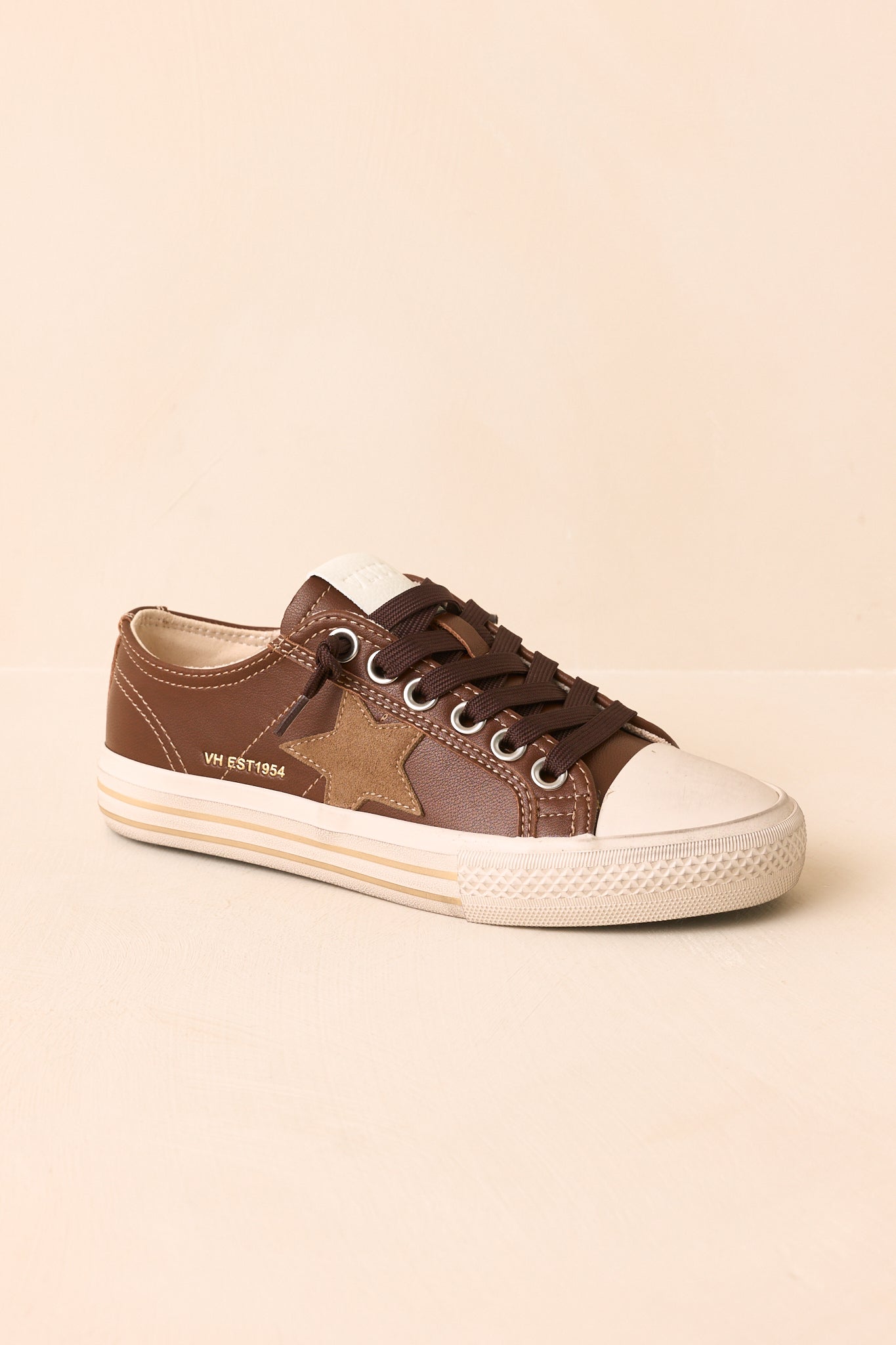 Angled view of the low-top sneakers featuring an ivory toe cap and rich brown color palette.