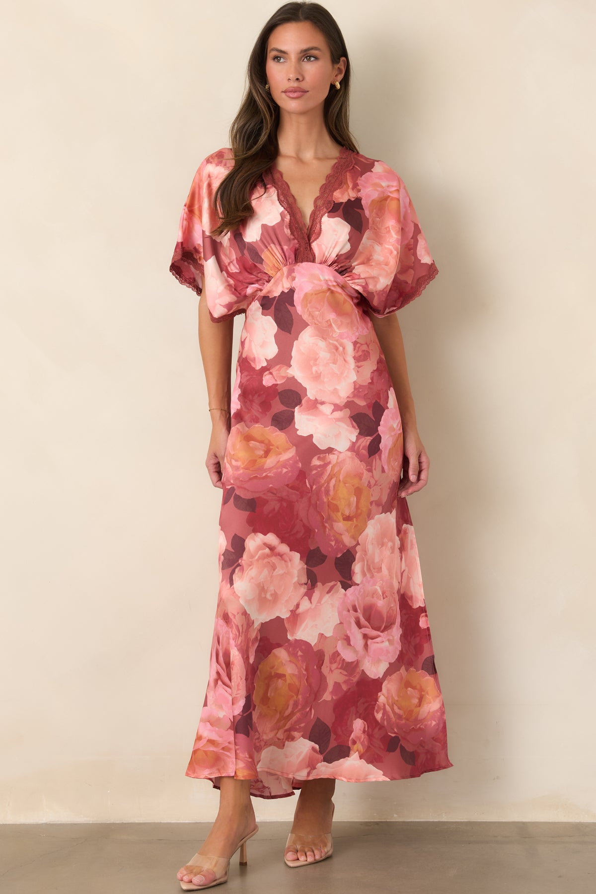 Lustrous floral satin dress showcasing warm coral and blush blooms across its graceful floor-length silhouette.