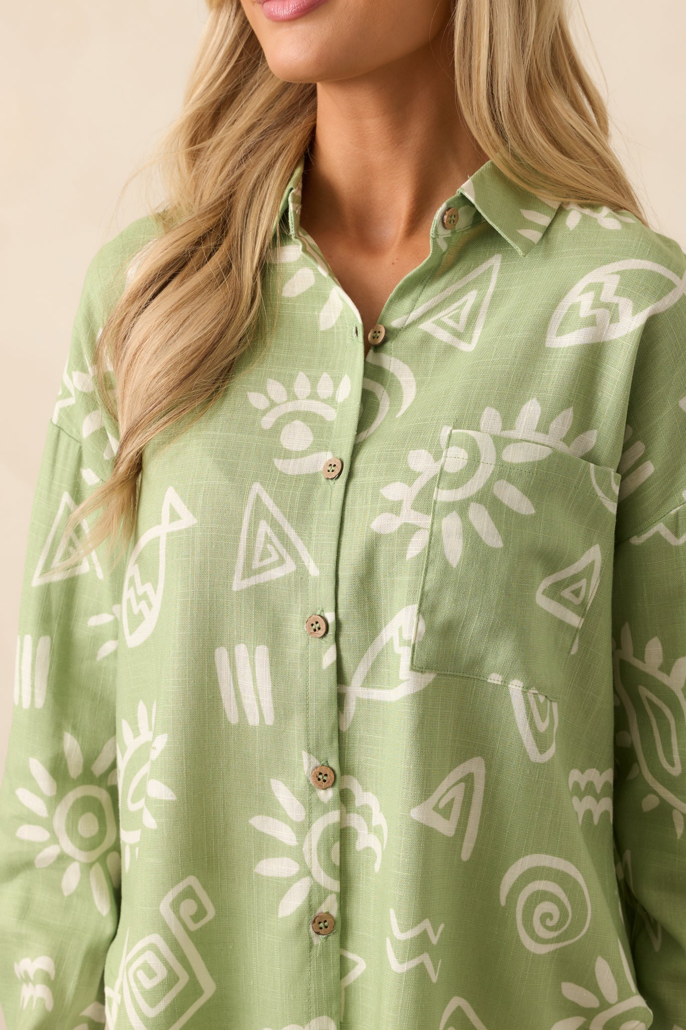 Macro view of the button cuff and sleeve showcasing the ivory tropical print and precise stitching on the functional cuff.