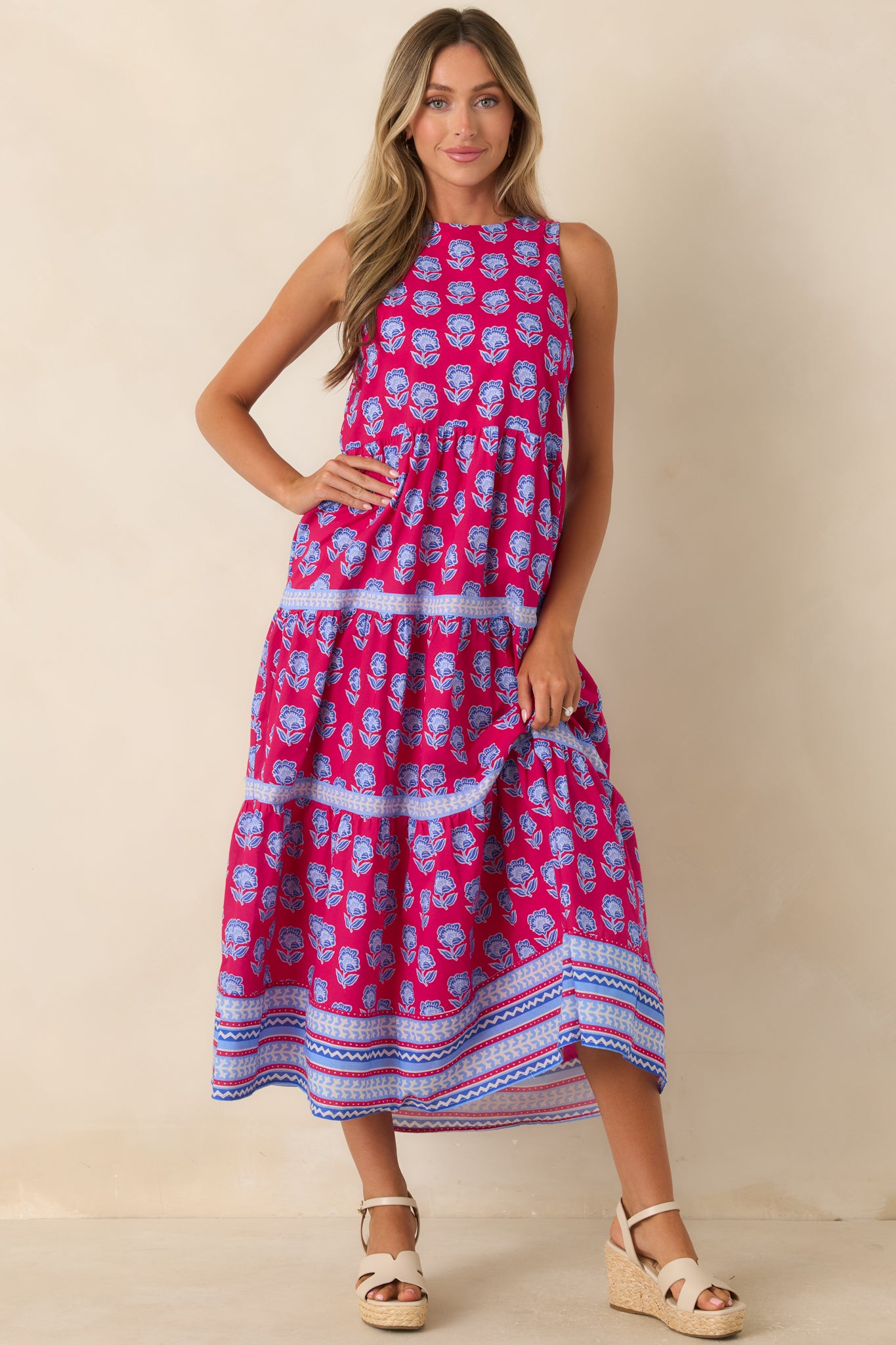 Sleeveless cotton midi dress showcasing a magenta backdrop, soft blue florals, and graceful tiered layers.