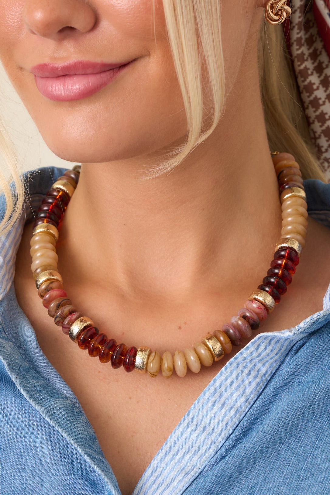 Close-up of the necklace highlighting the rounded disc beads, marbled surfaces, translucent earthy tones, and textured gold-tone accents.