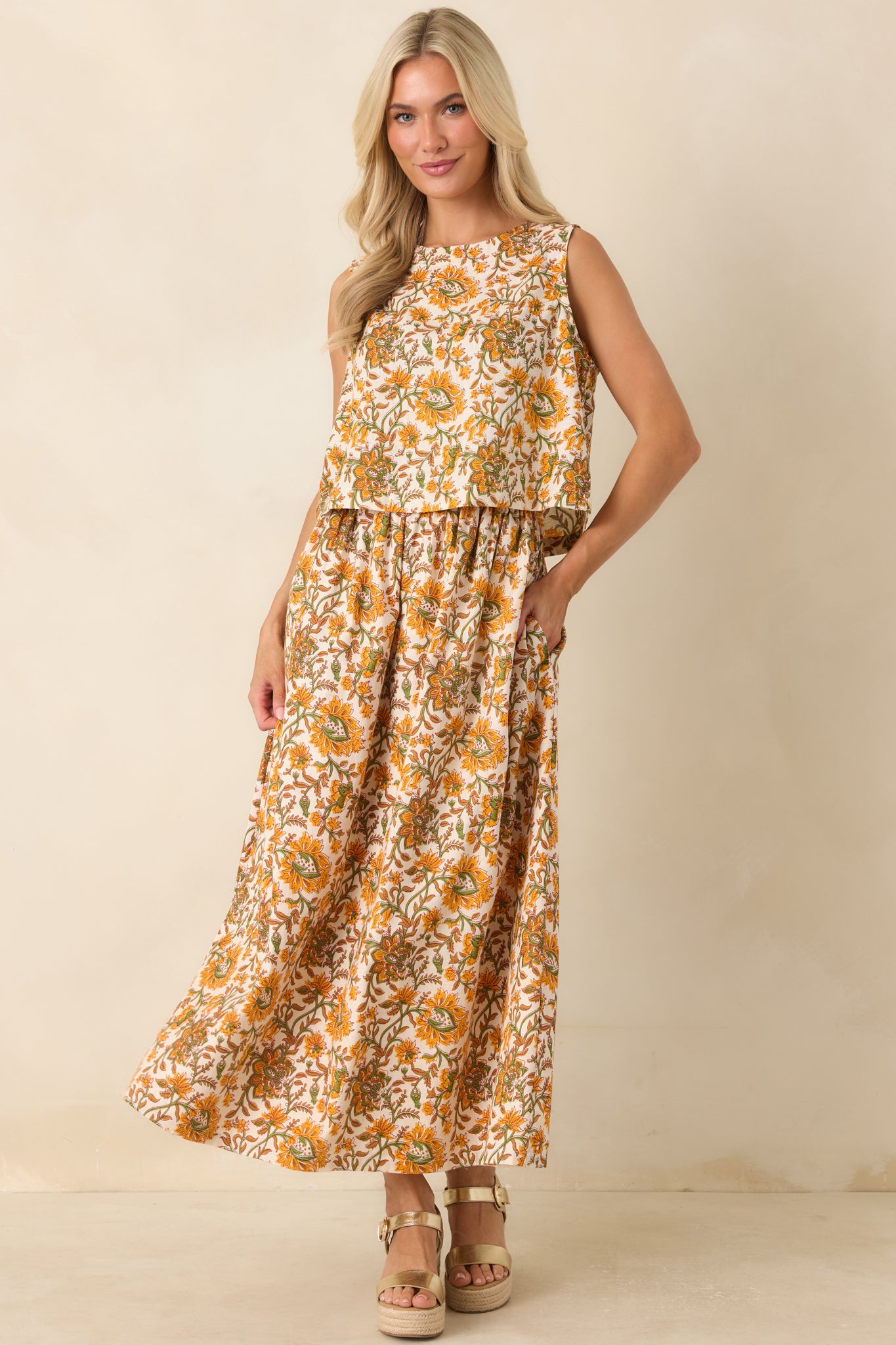 Full-length view of a maxi skirt featuring a marigold and olive floral print on an ivory background with a comfortable elastic waistband and side pockets.
