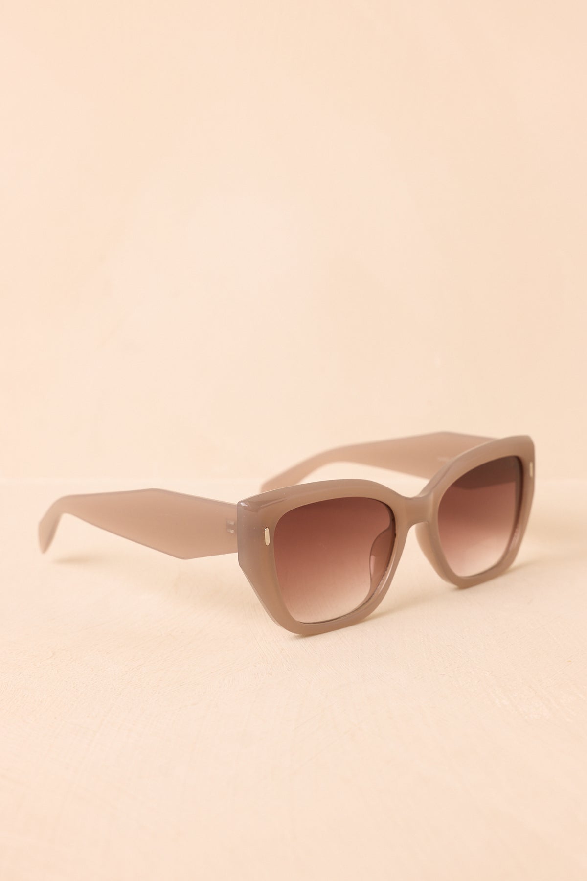 Mauve taupe sunglasses with wide arms, gold-tone accents, and oversized lenses.