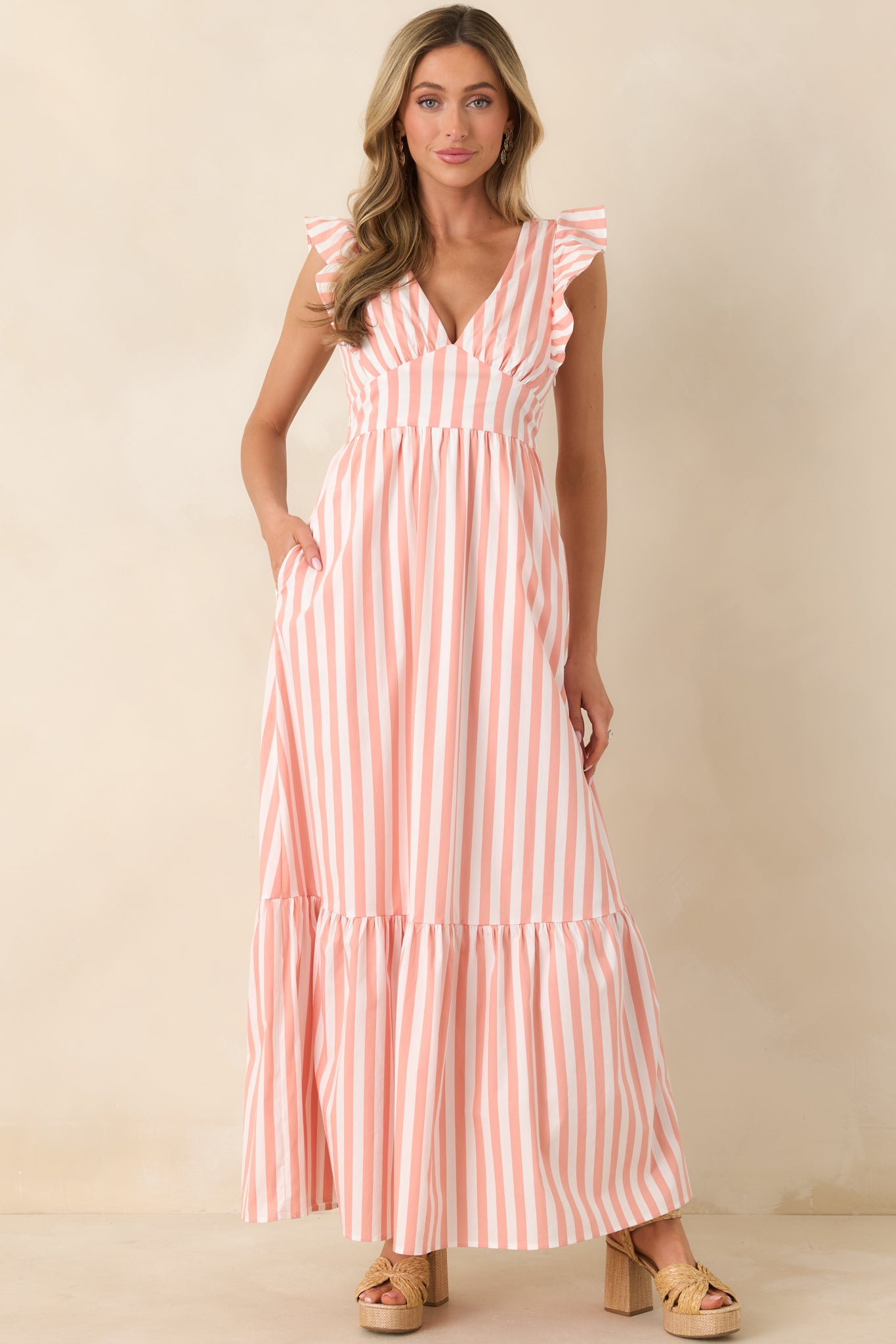 Maxi dress combining a deep V-neckline, wide flutter straps, fitted bodice, and layered skirt that moves freely with each step.