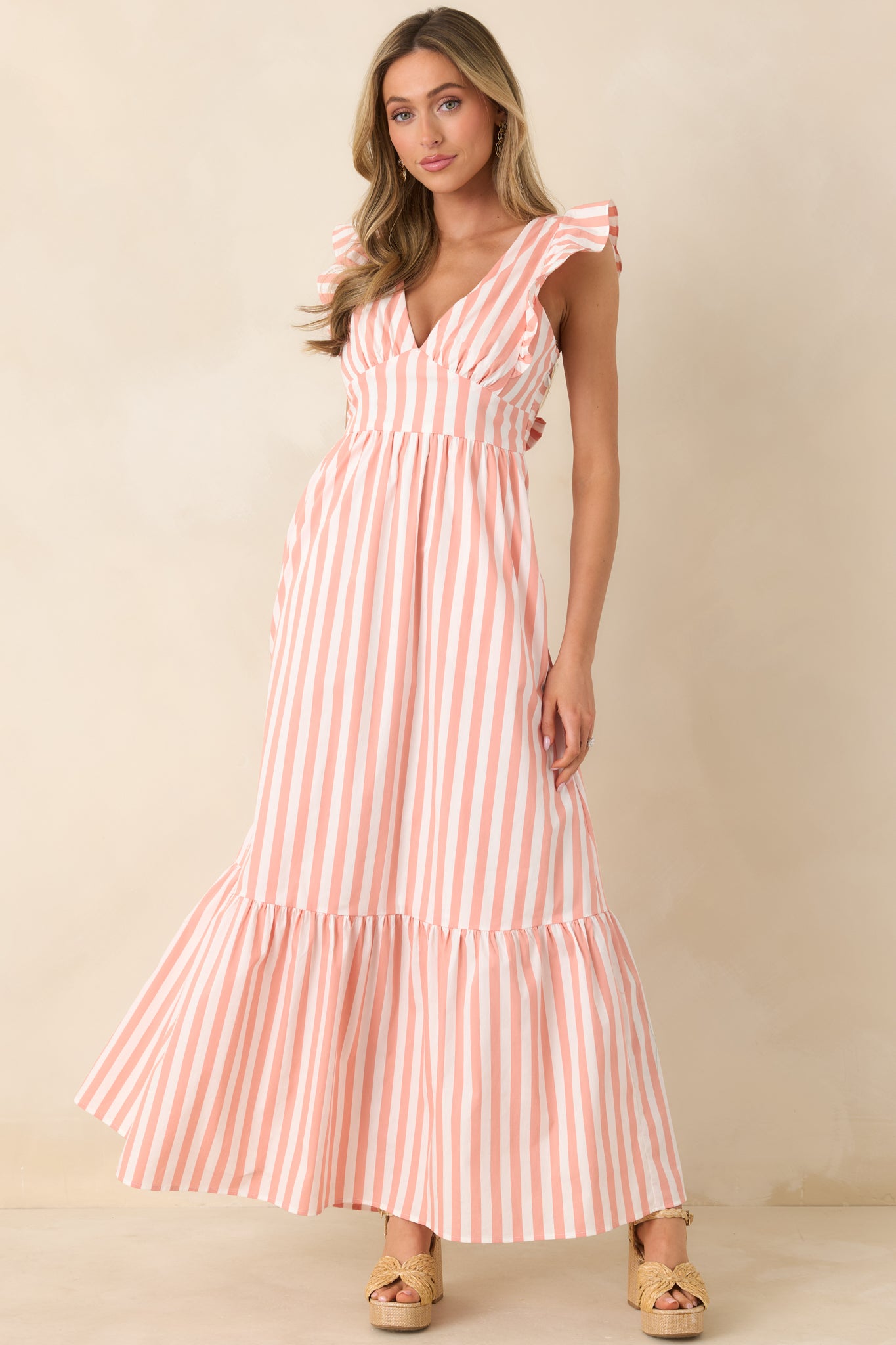Maxi dress with a plunging neckline, wide flutter straps, fitted bodice, and a flowing tiered skirt creating a romantic, elongating silhouette.