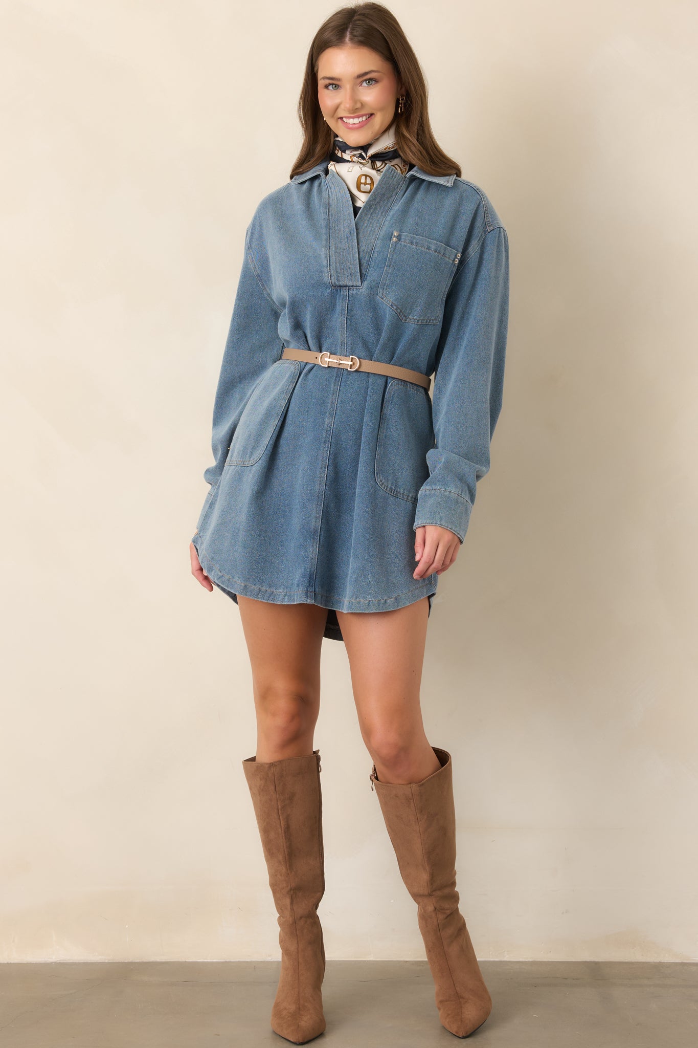Medium indigo denim mini dress featuring a collared neckline, partial button placket, long cuffed sleeves, relaxed fit, and straight mini-length hem.