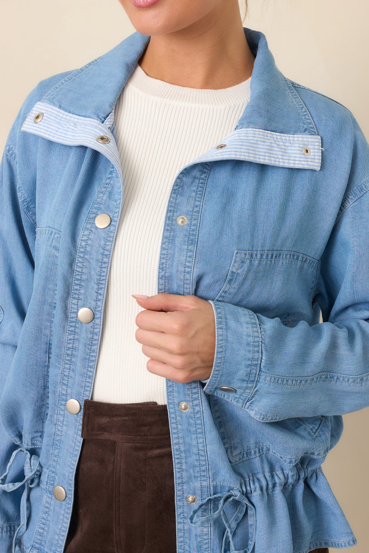 Close view of the medium wash denim texture, classic collar, and silver-tone snap detailing.