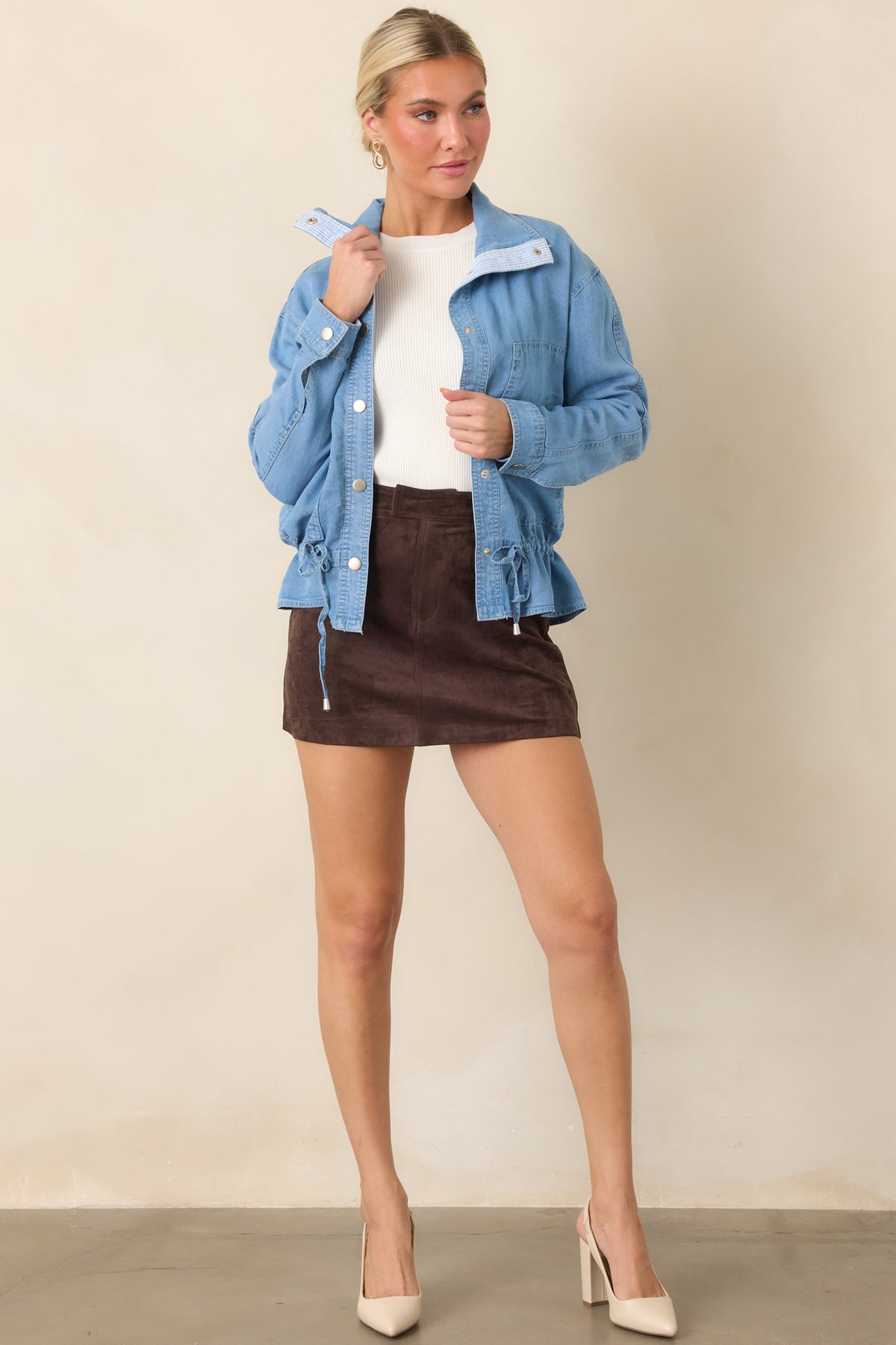 Relaxed medium wash denim top featuring long sleeves, silver-tone snaps, and a subtle peplum shape.