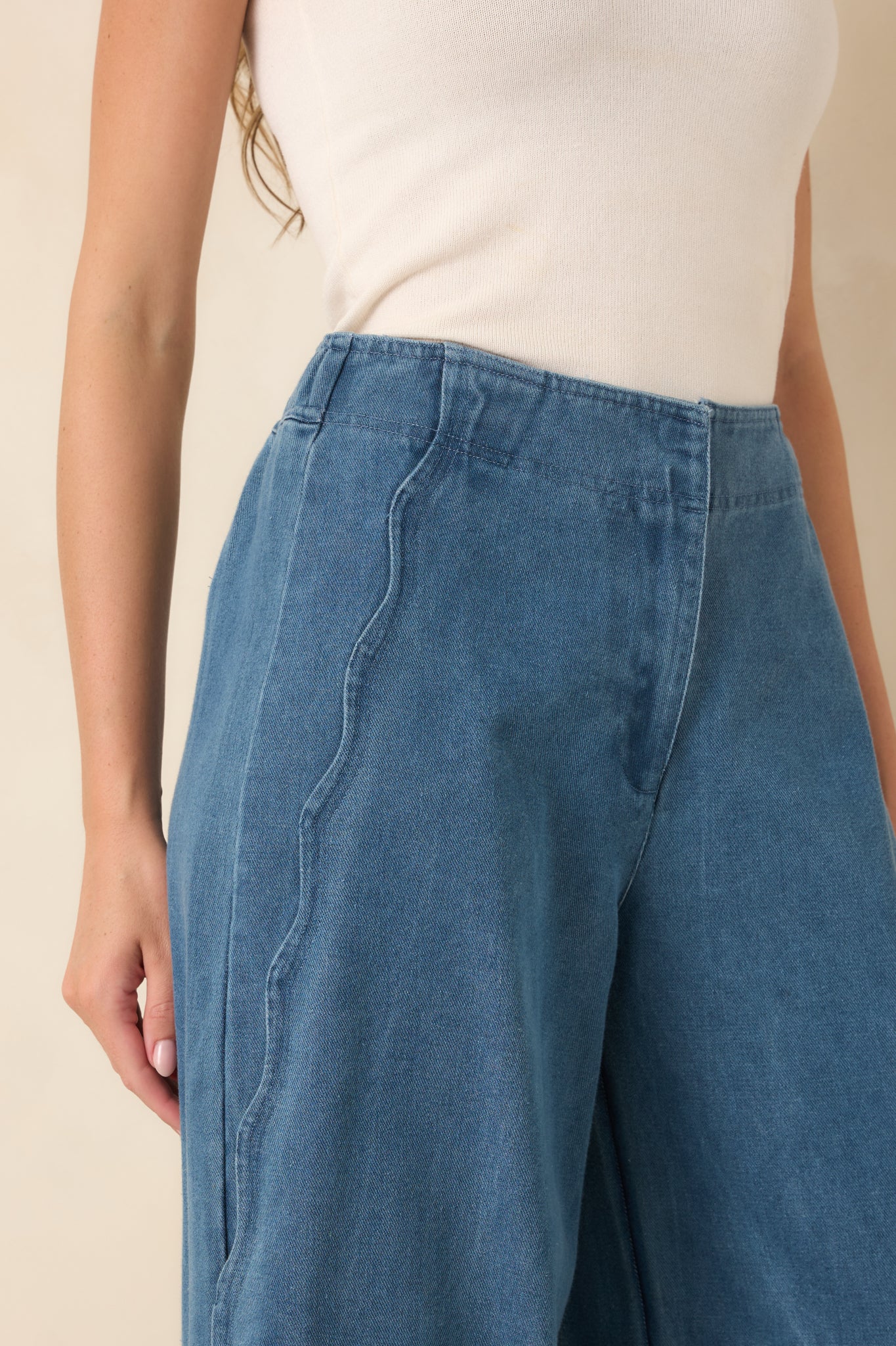 Close-up of the medium wash denim highlighting the hidden front zip closure, curved scalloped side seams, and classic jean construction.