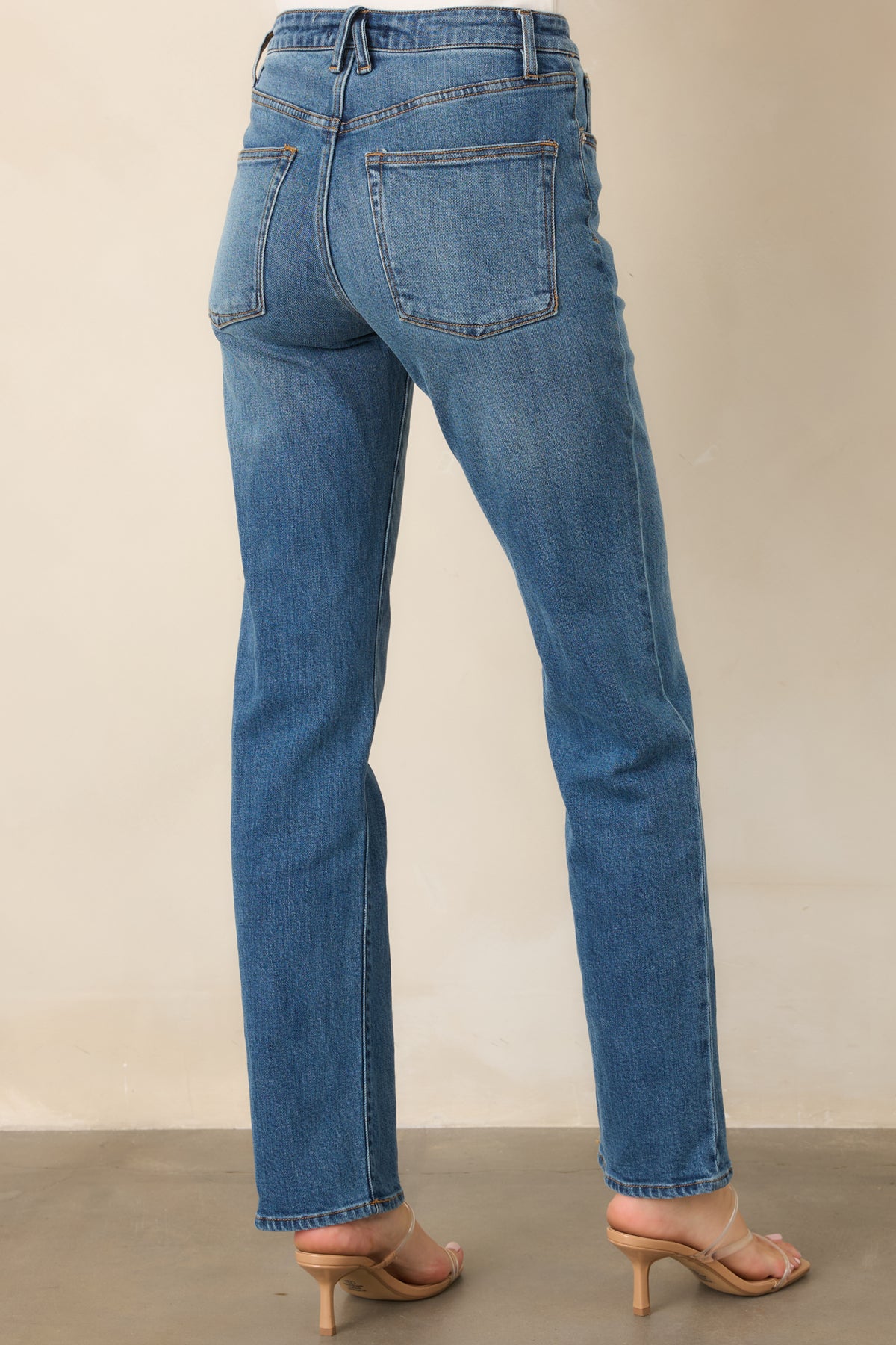 Rear of medium wash jeans showing straight legs and five-pocket styling.